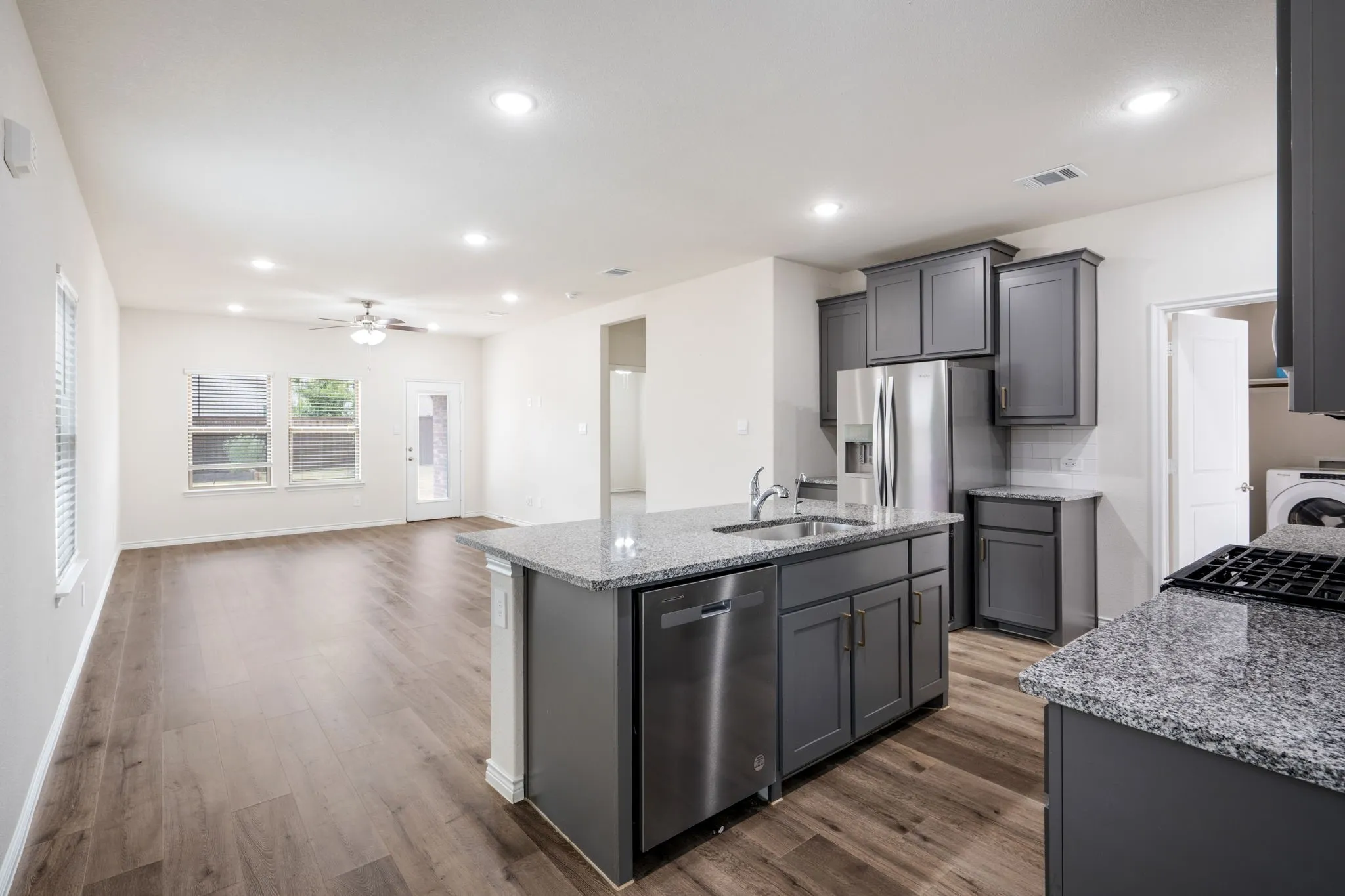 Open-concept living space featuring wood-finish flooring, recessed lighting, and a ceiling fan