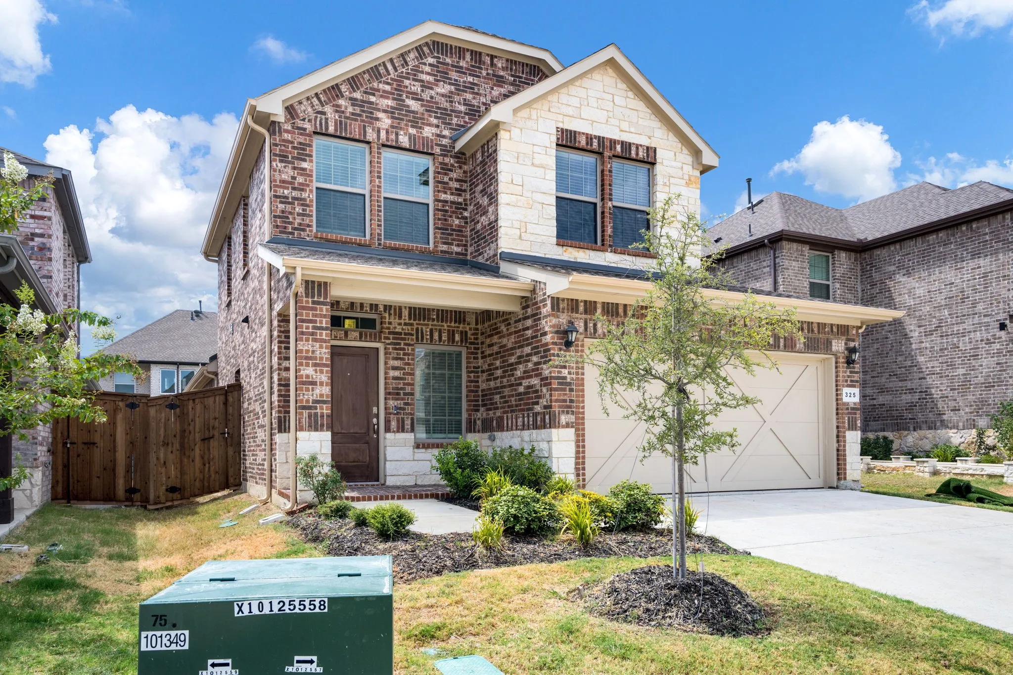 Brick and stone facade with a covered entry, two-car garage, and established landscaping