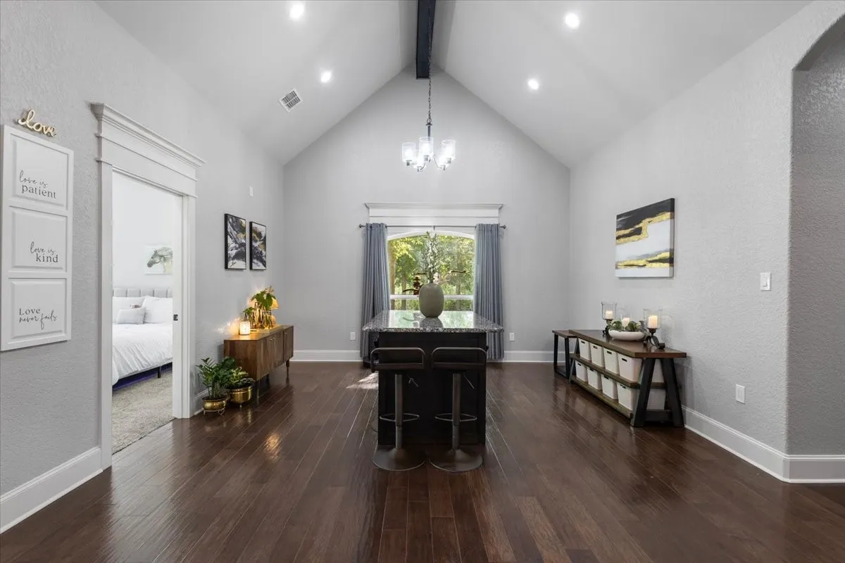 Vaulted ceiling with an exposed beam, recessed lighting, wood-finish flooring, and a kitchen island with seating