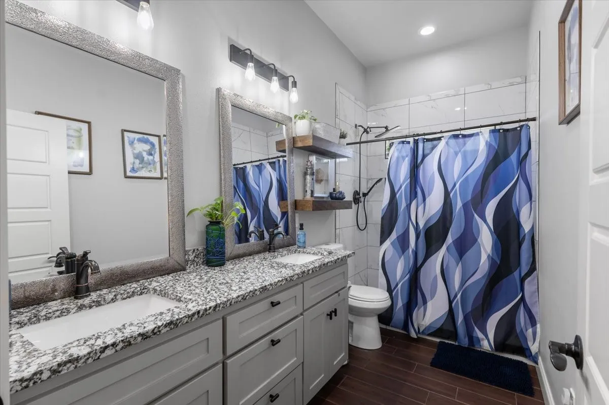 Double vanity with granite-style countertop, dual rectangular undermount sinks, and dark bronze-finish fixtures