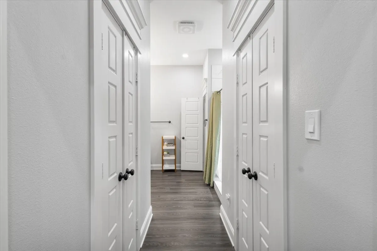 Hallway with wood-finish flooring, white panel doors, and recessed lighting