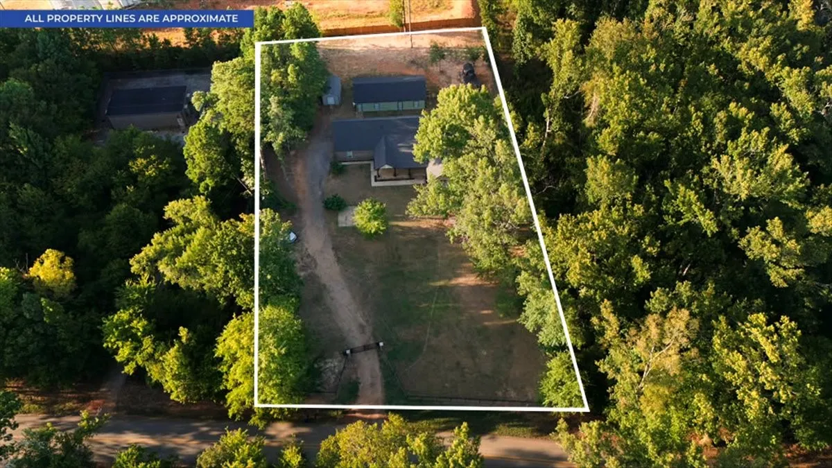 Expansive property featuring a main residence, secondary structure, and surrounding mature trees