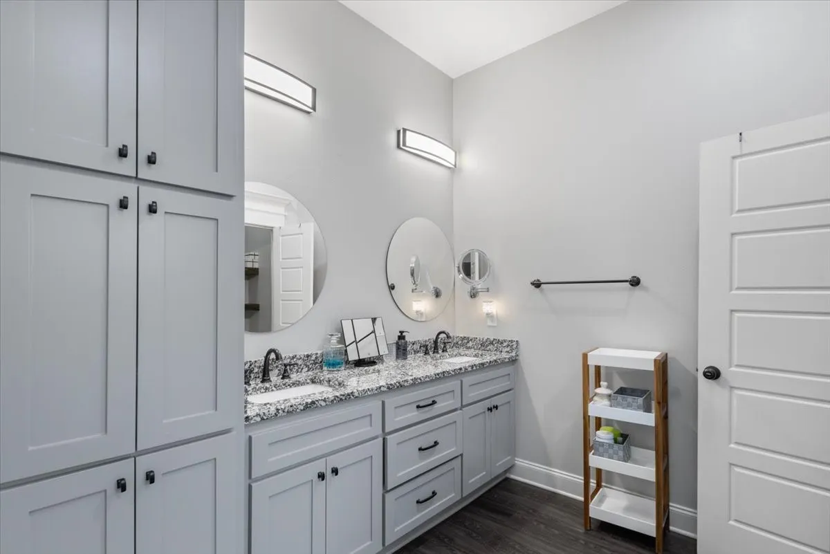 Dual vanity with undermount sinks, speckled countertop, and wall-mounted light fixtures