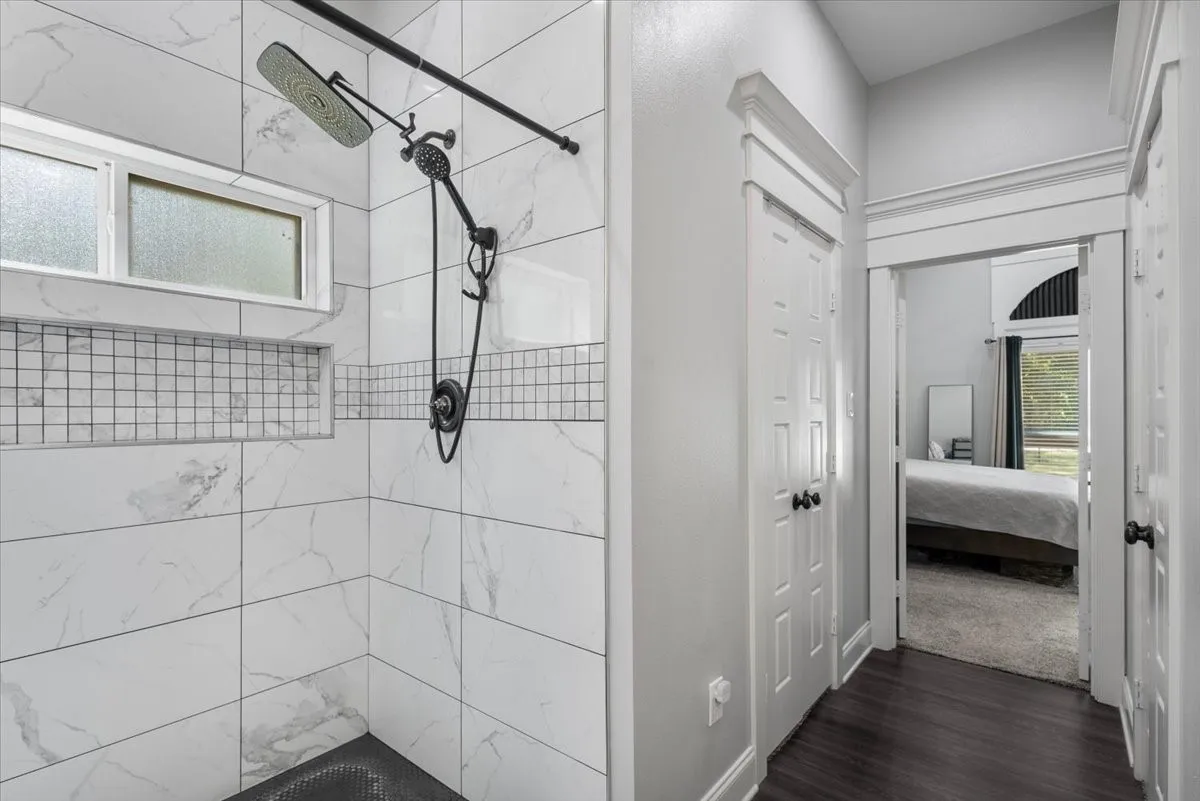 Shower featuring white tile walls, black grid accent tile, a built-in shower niche, and a fixed window