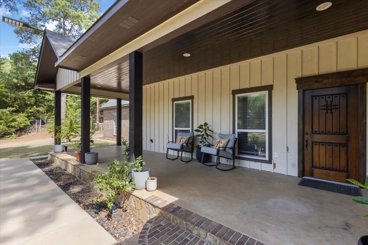 Expansive covered porch with dark wood columns and recessed lighting