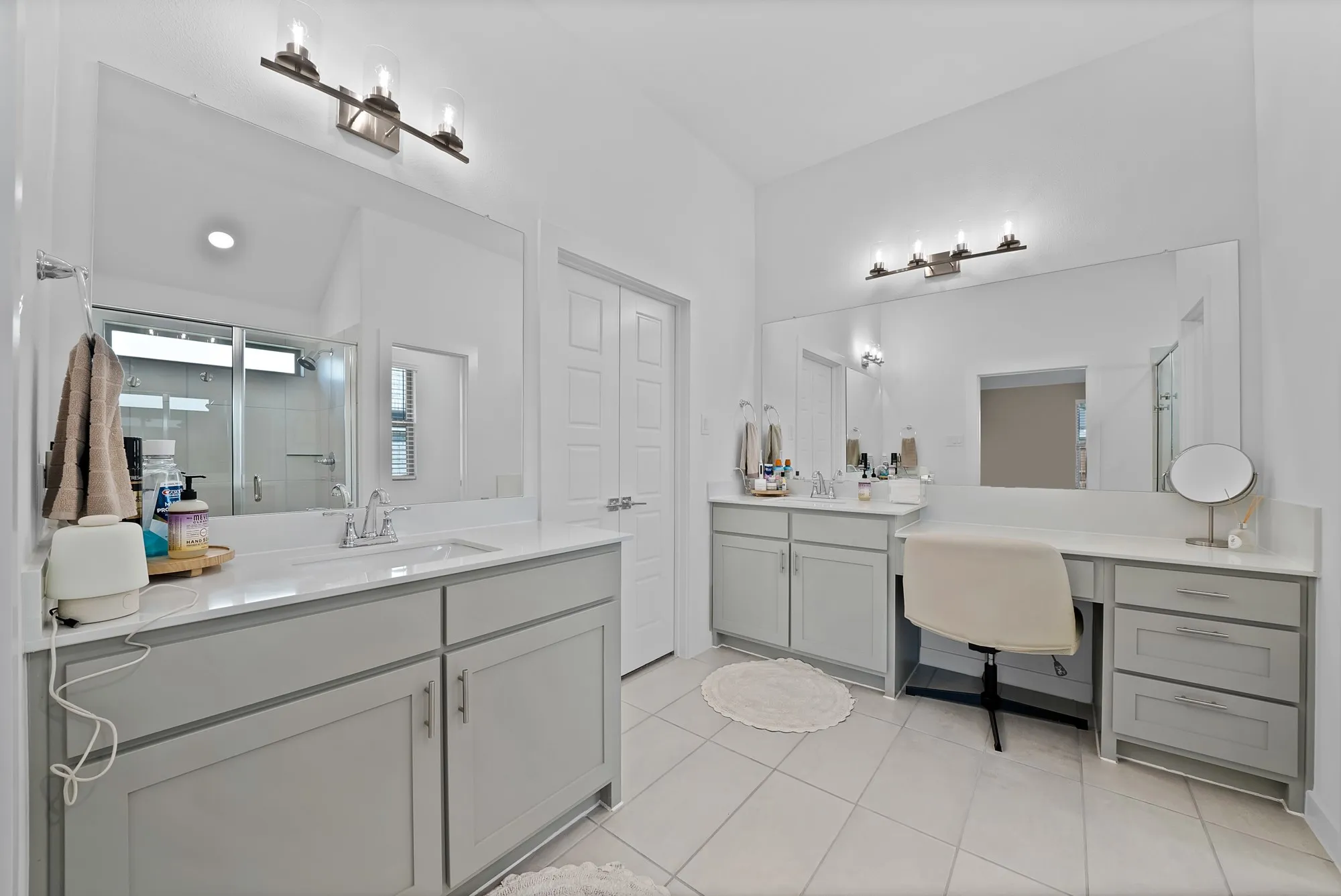 Dual vanities with undermount sinks, integrated vanity counter, light gray cabinetry, and tile flooring.