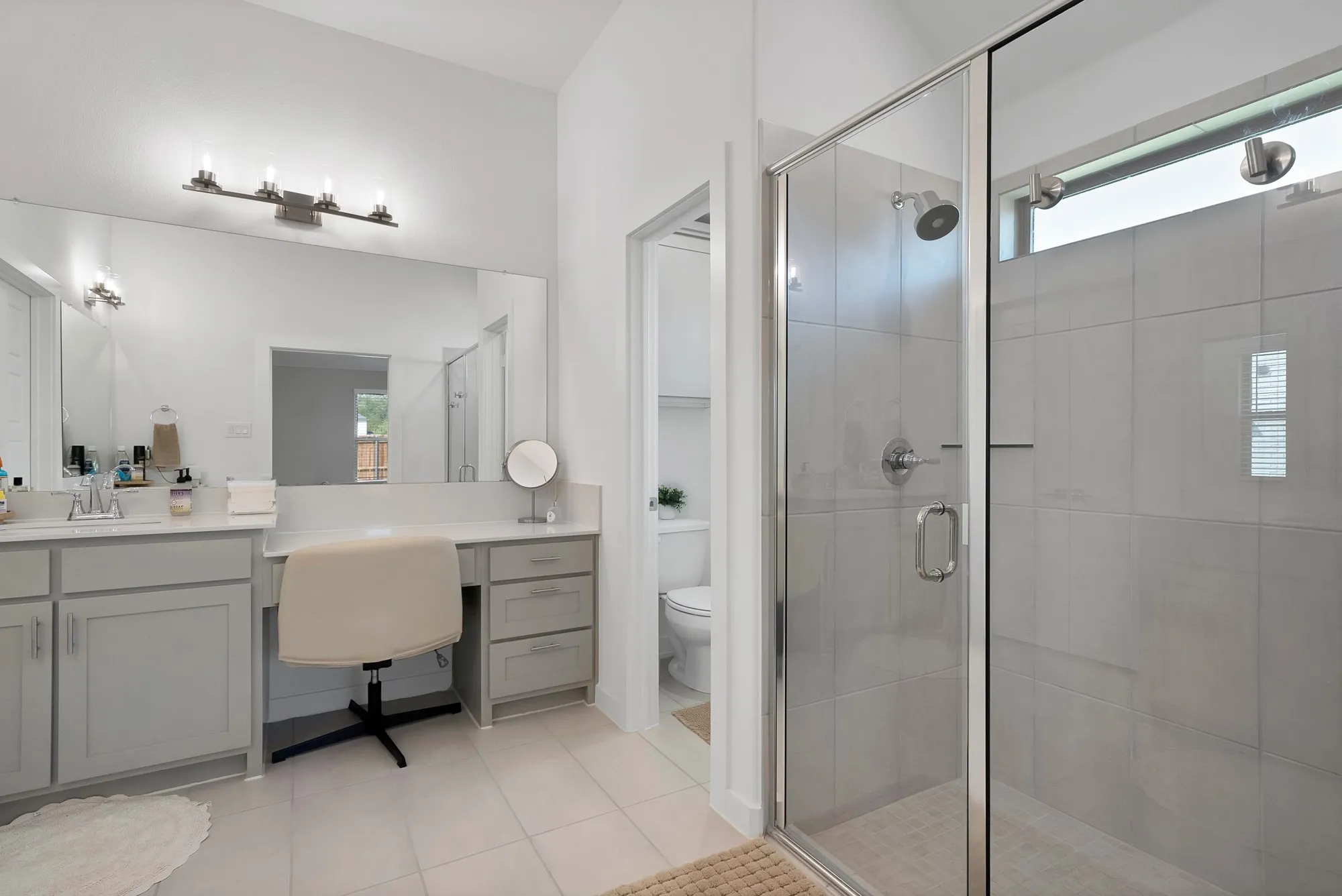 Glass-enclosed shower with tile surround and transom window.