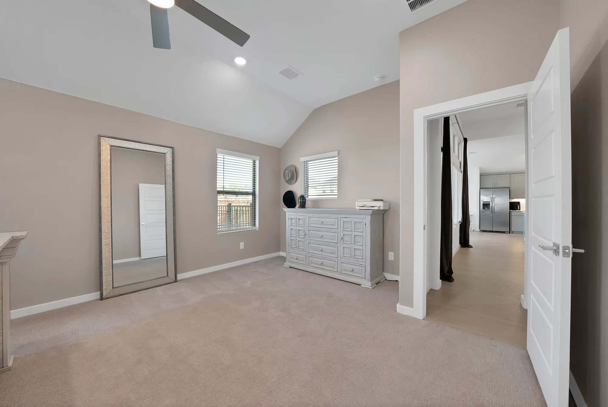 Vaulted ceiling with recessed lighting and ceiling fan that adorn this primary retreat.
