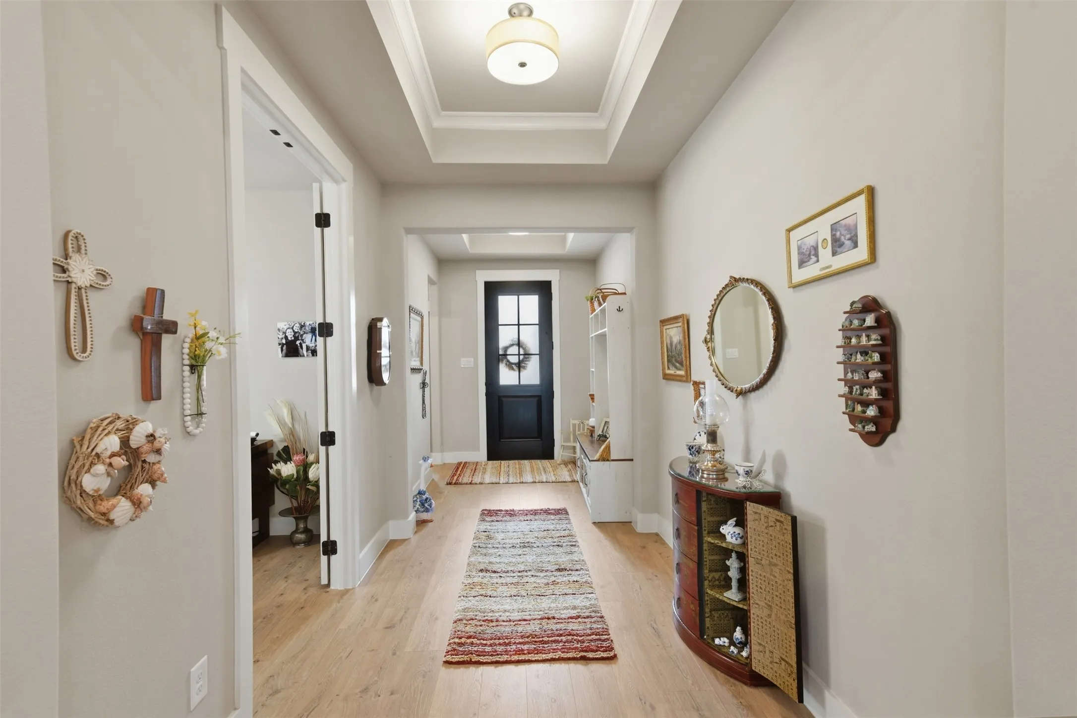 Recessed ceiling with central lighting fixture, light wood-finish flooring, and white trim throughout