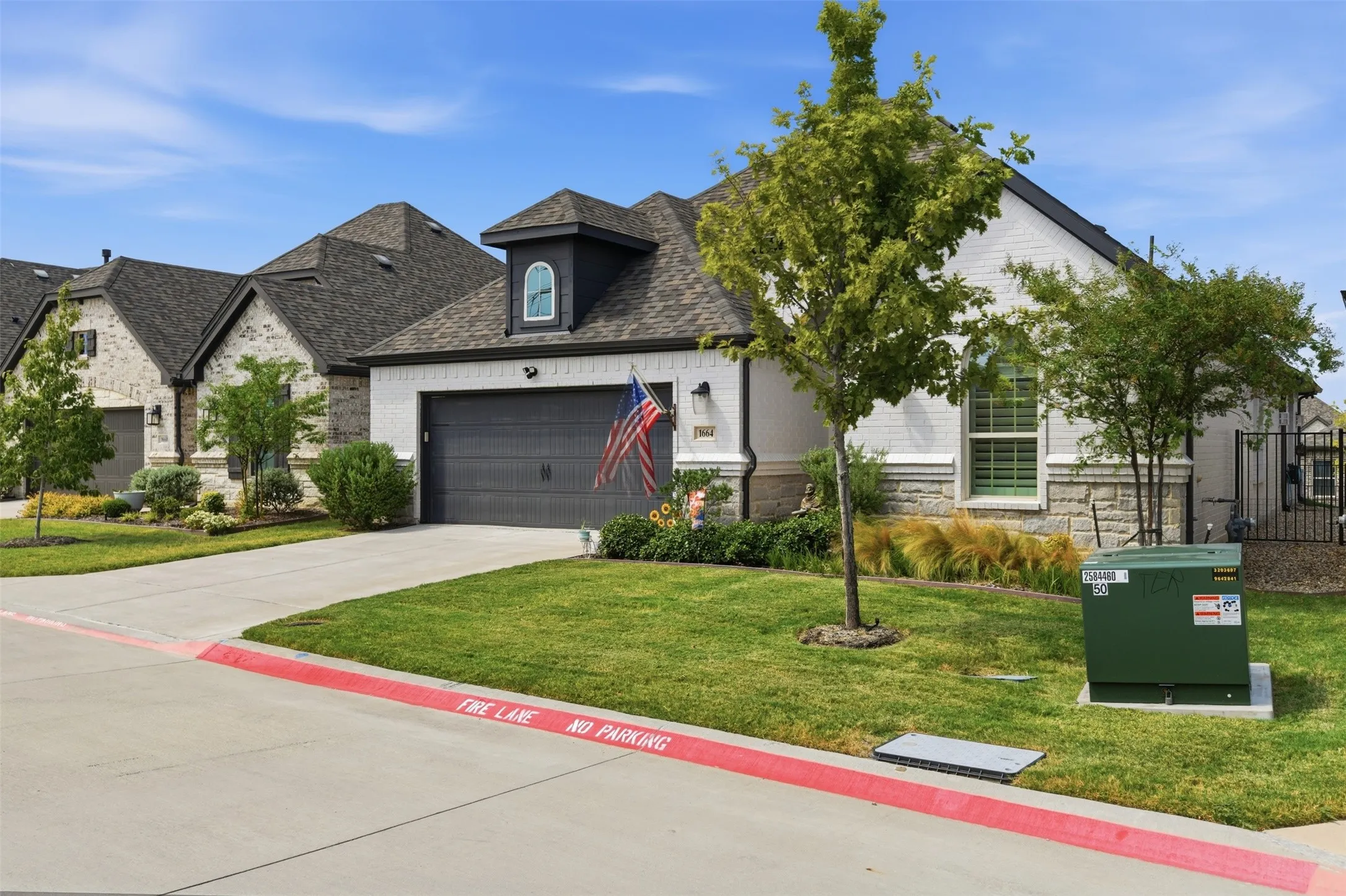 Modern exterior with brick and stone accents, a dark gray garage door, and a prominent dormer window