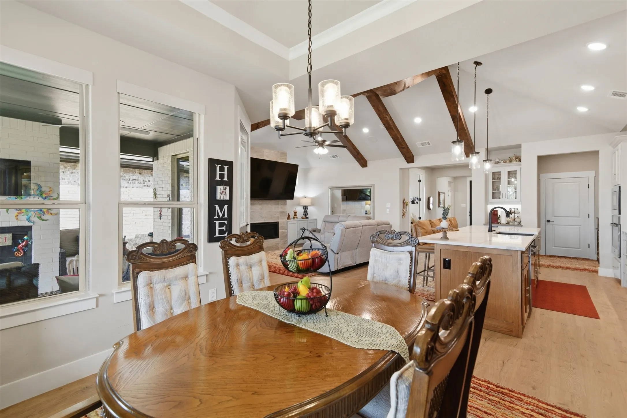 Vaulted ceiling with exposed wood beams, wood-finish flooring, recessed lighting, kitchen island with countertop, and pendant lighting