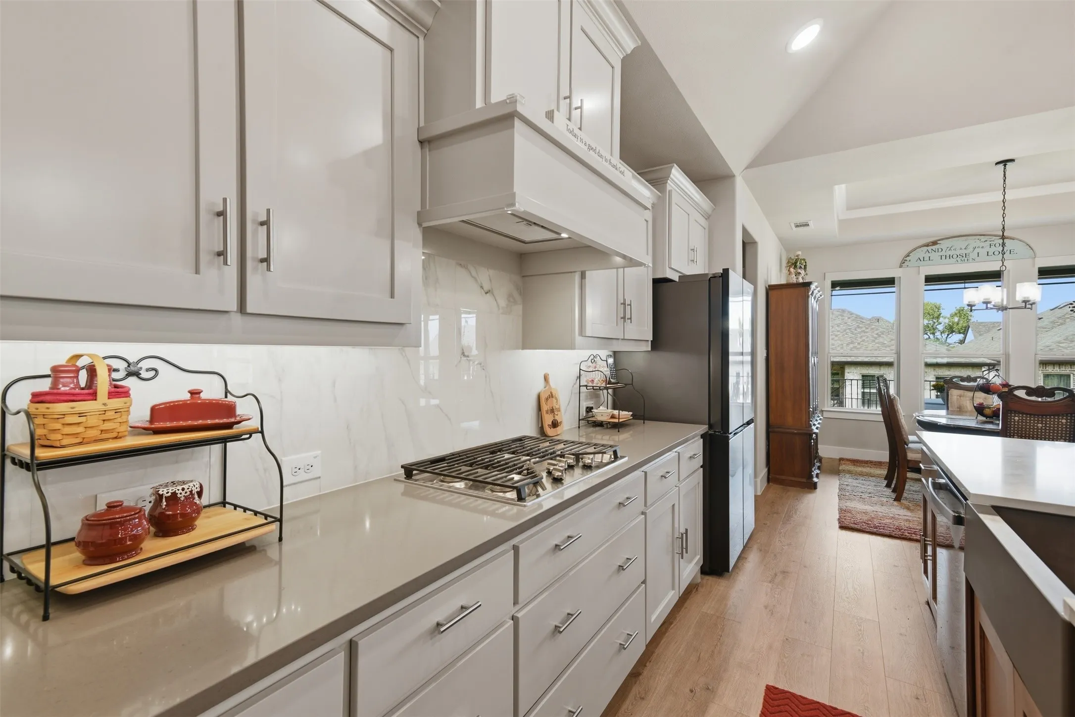 Kitchen featuring light-toned cabinetry, a gas cooktop, light countertops, and a full-height backsplash