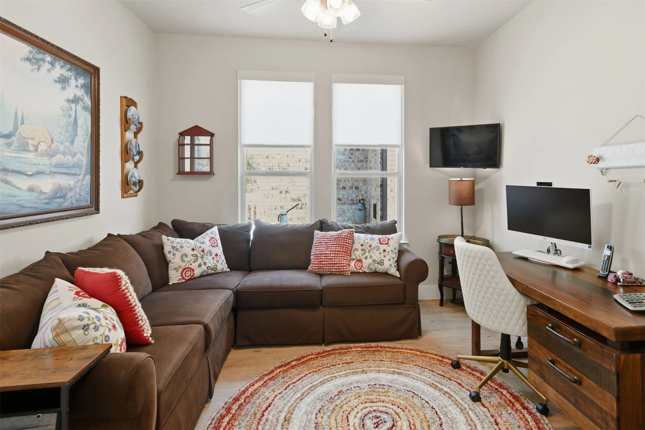 Light wood-finish flooring, ceiling fan, and two windows providing natural light