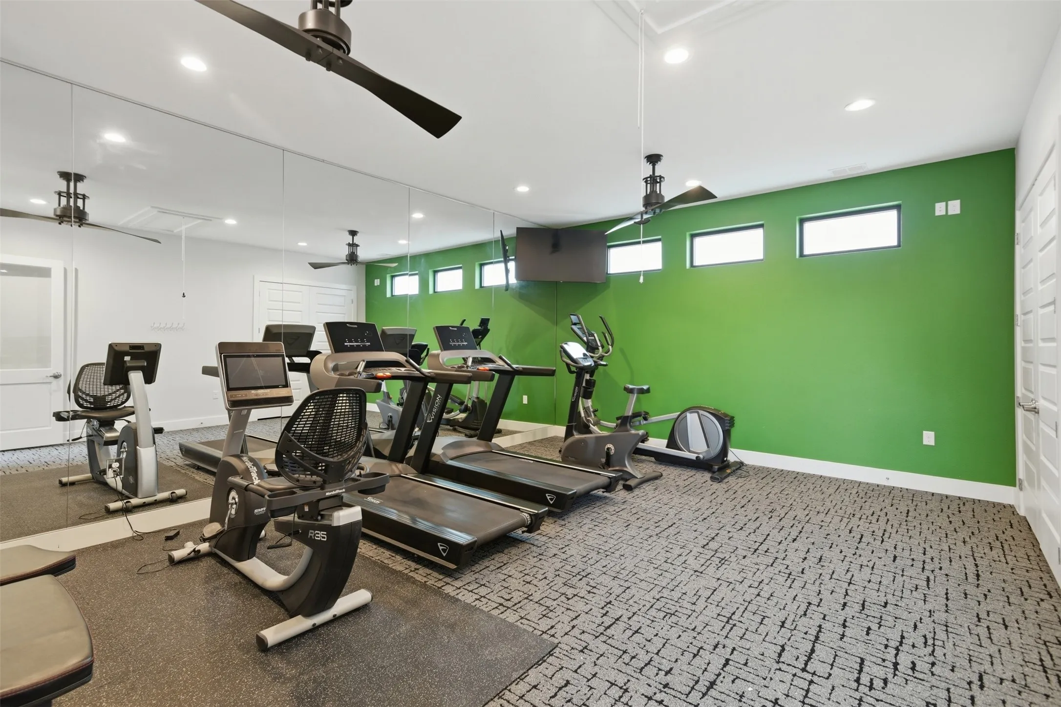 Dedicated fitness space featuring full-wall mirrors, recessed lighting, and ceiling fans