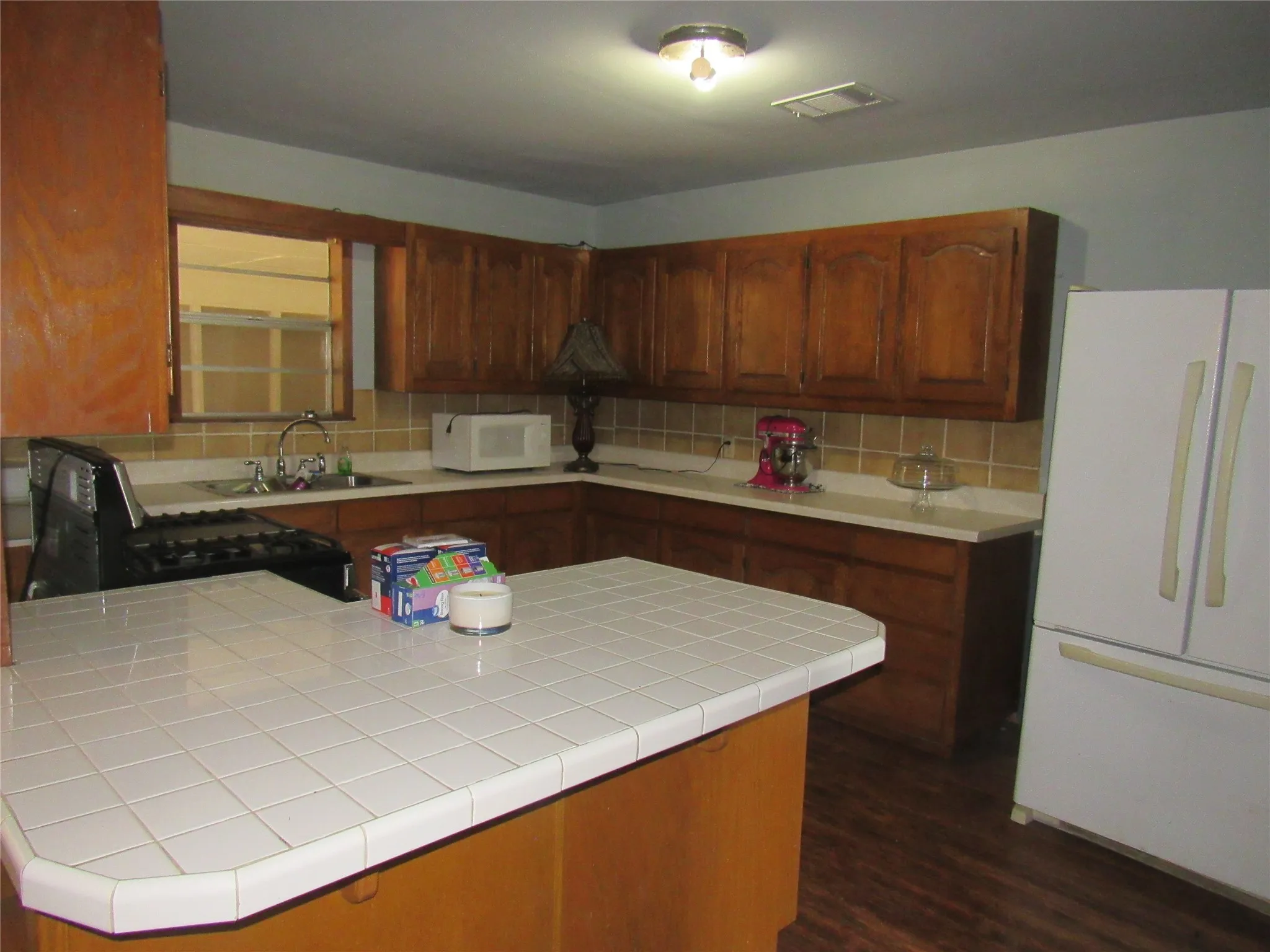 Kitchen featuring wood-finish cabinetry, tile countertops, a built-in gas range, and a dual-basin sink
