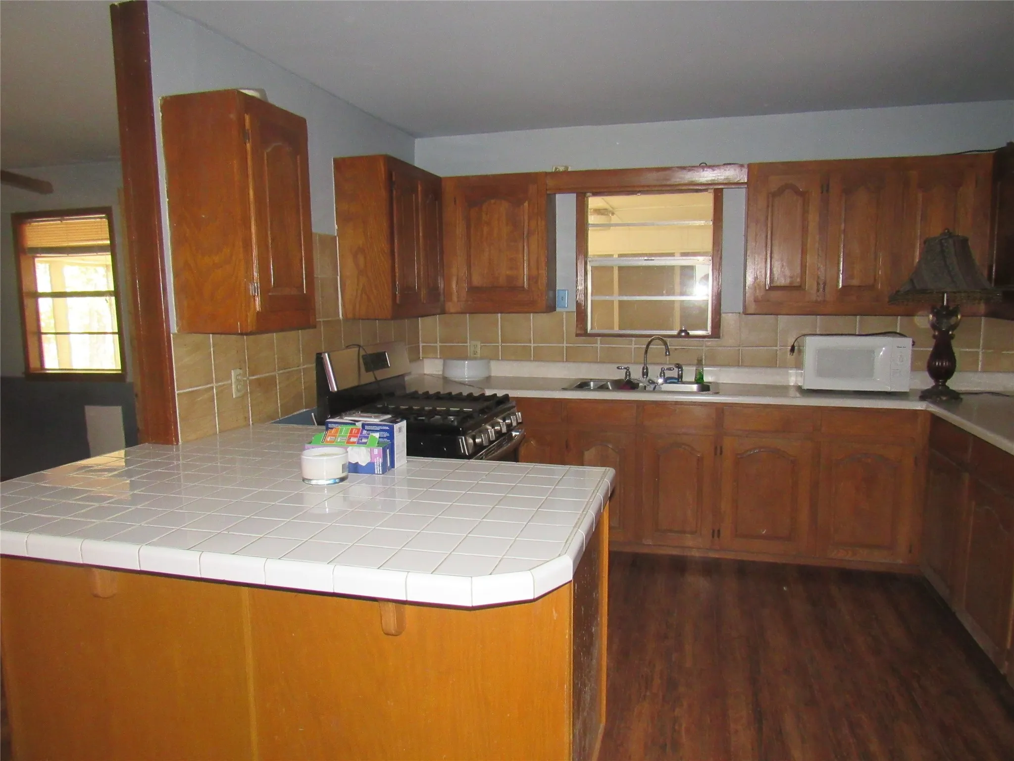 Kitchen featuring wood-finish flooring, wood cabinetry, tile backsplash, and a built-in gas range