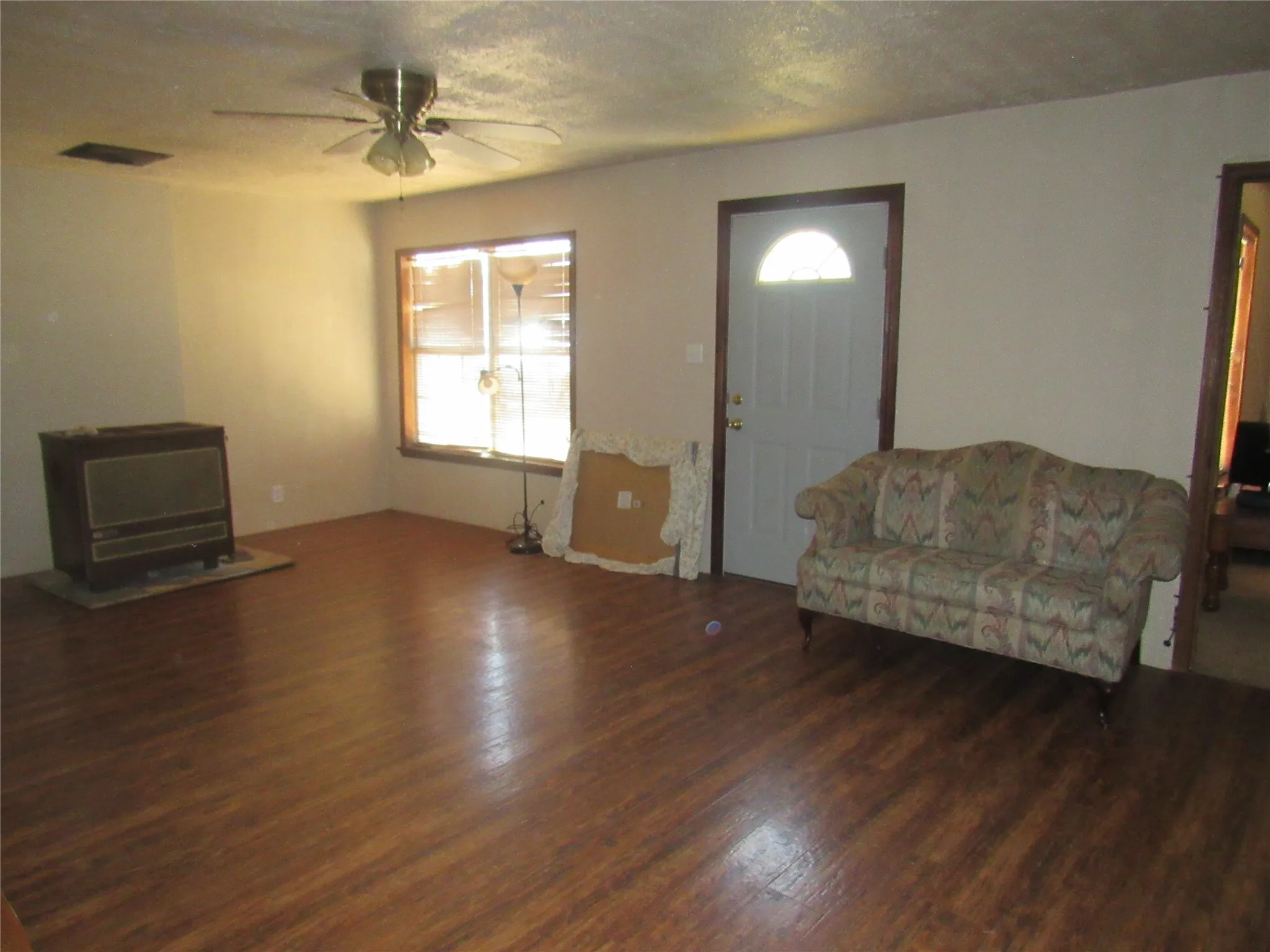 Wood-finish flooring, ceiling fan, and a front entry door with an arched window insert