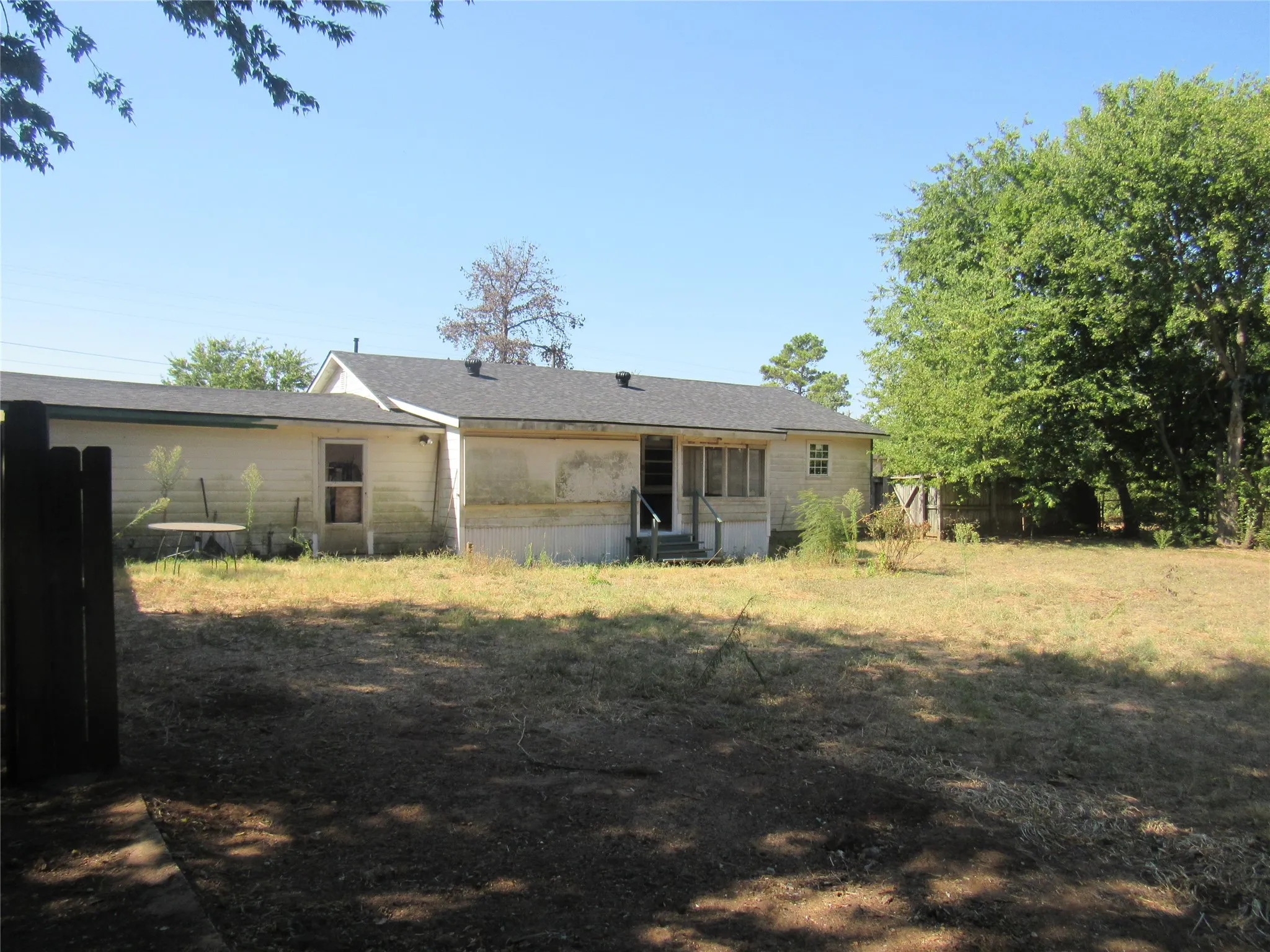 Rear property exterior with a dark shingle roof and a wooden fence
