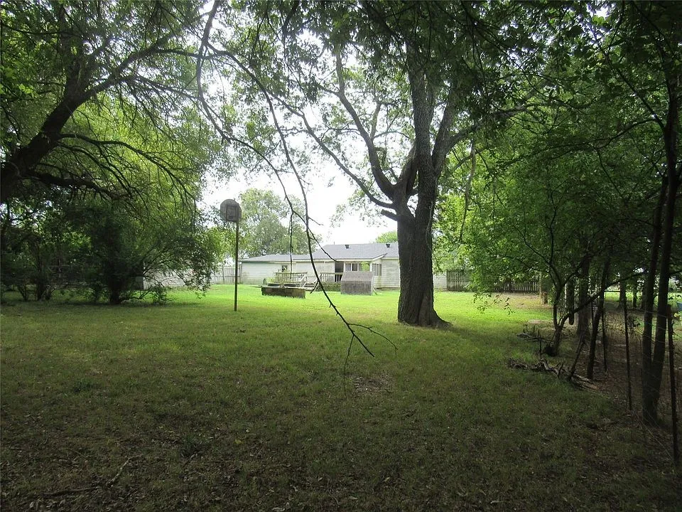 Expansive yard featuring mature trees and a grassy area