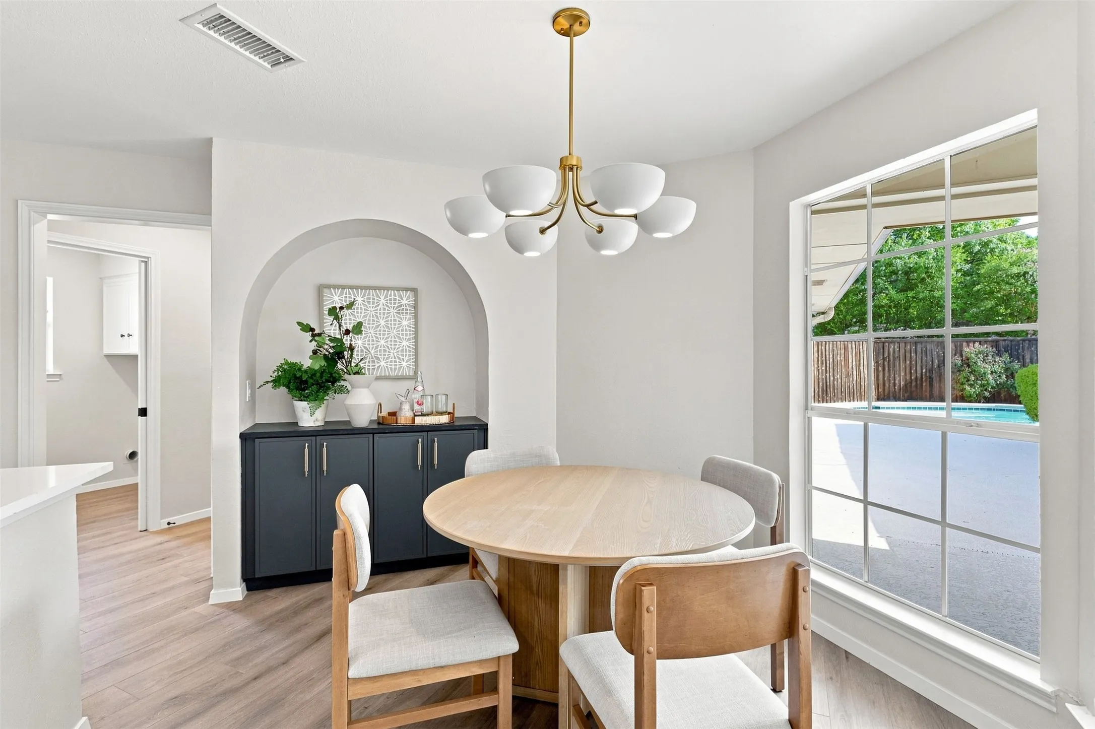 Arched built-in cabinetry with a countertop, wood-finish flooring, and a multi-bulb chandelier