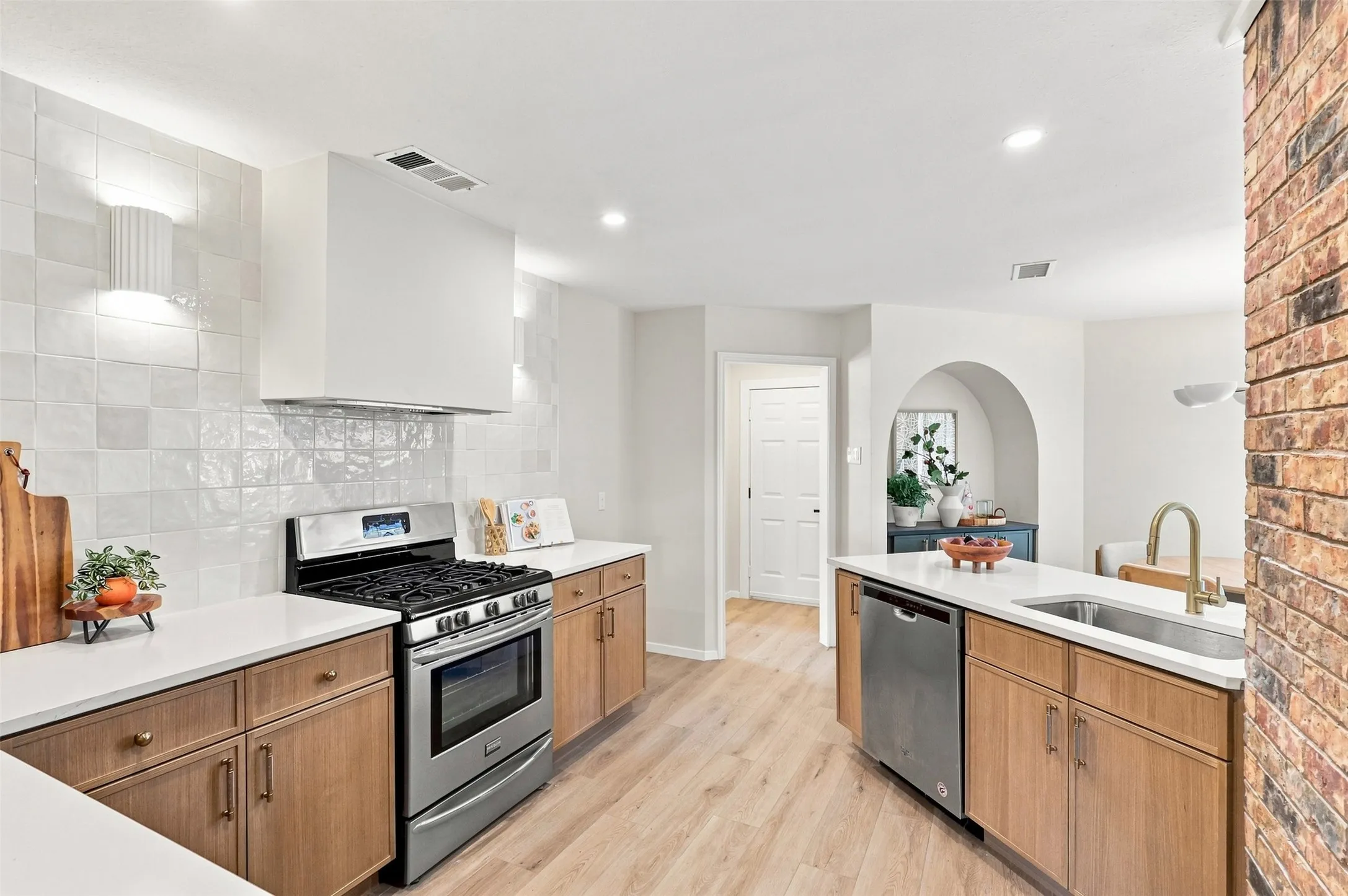 Kitchen featuring stainless steel appliances, wood-finish cabinetry, white countertops, and a full tile backsplash