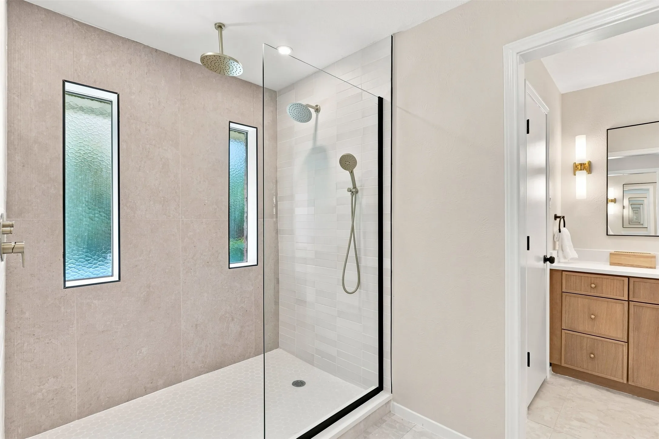 Glass-enclosed shower with a rainfall showerhead, handheld shower, and vertical accent windows