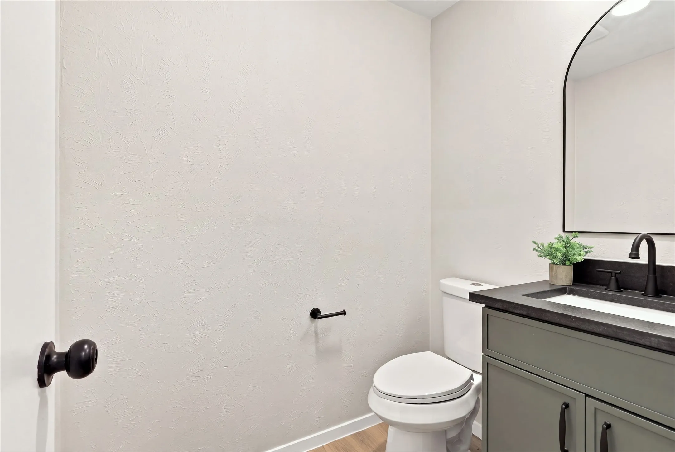 Vanity with a dark countertop, white basin, and matte black faucet