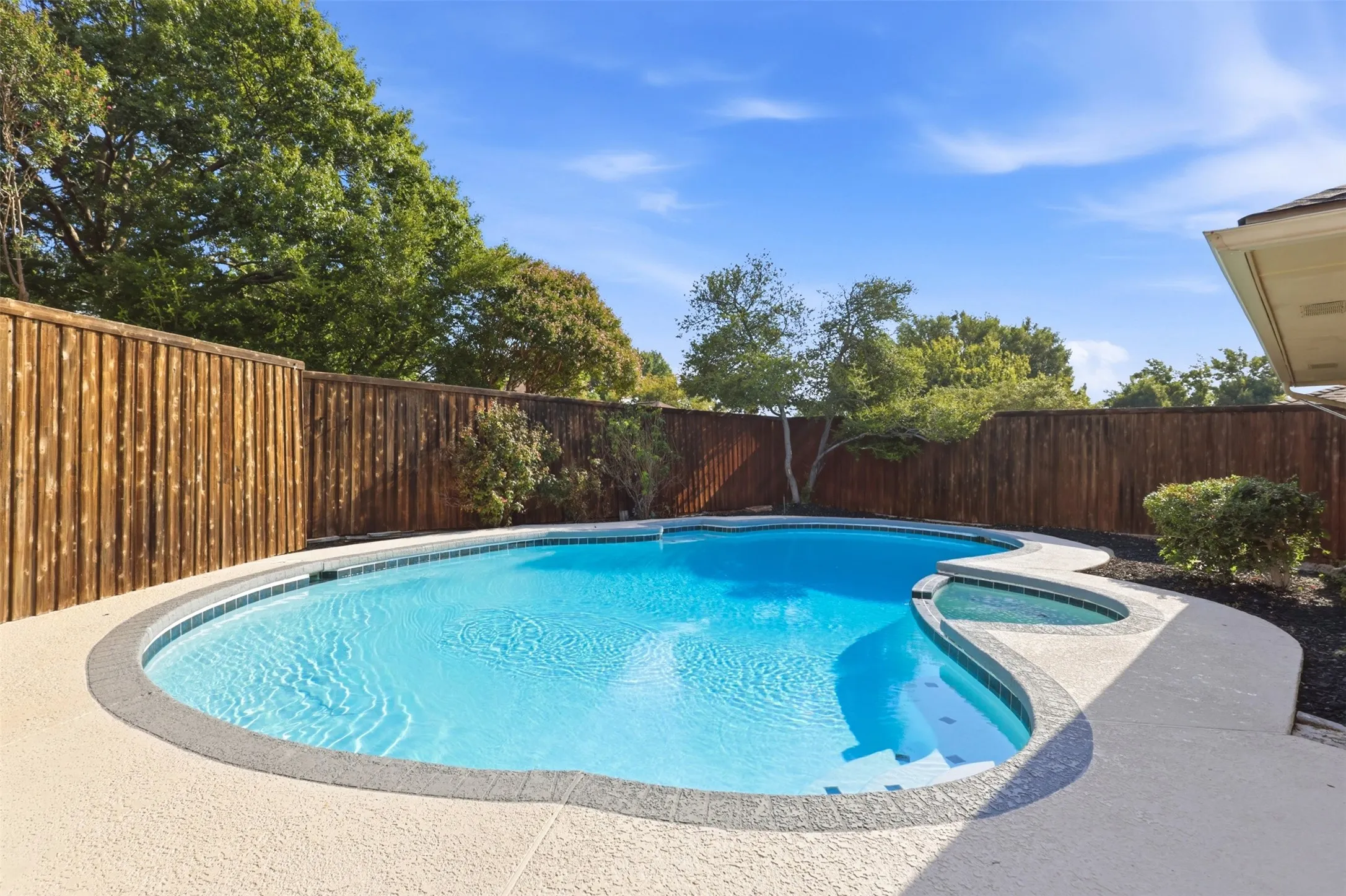 In-ground swimming pool with integrated spa and concrete decking