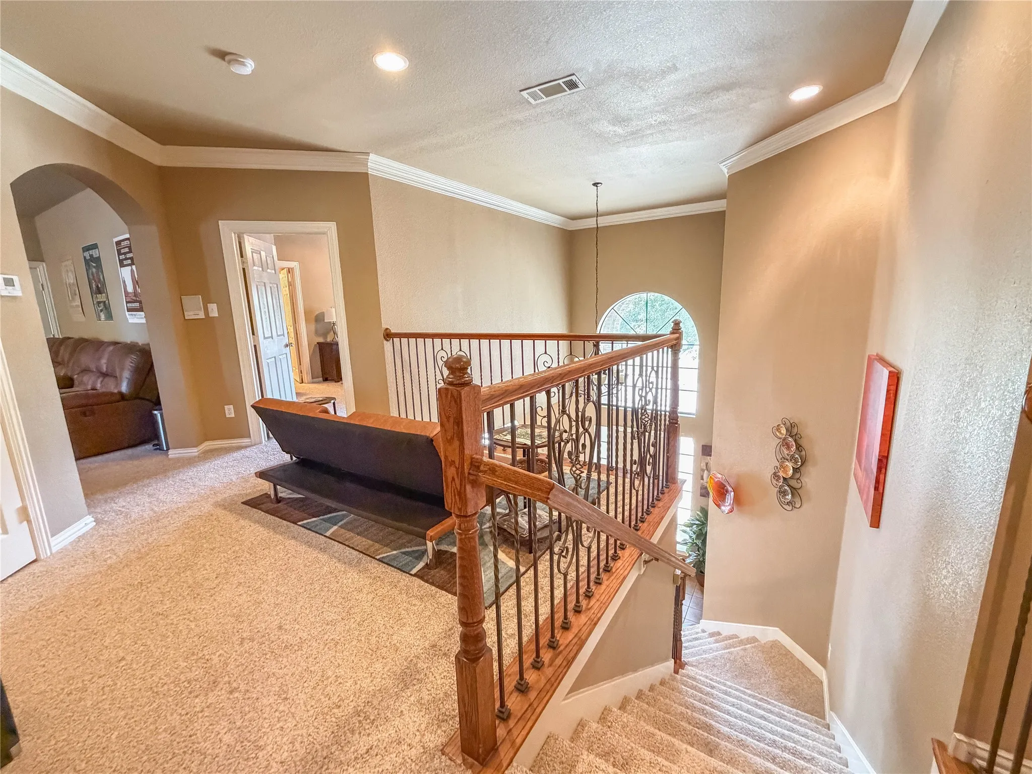 Carpeted staircase with wood-finish handrails and wrought iron balusters