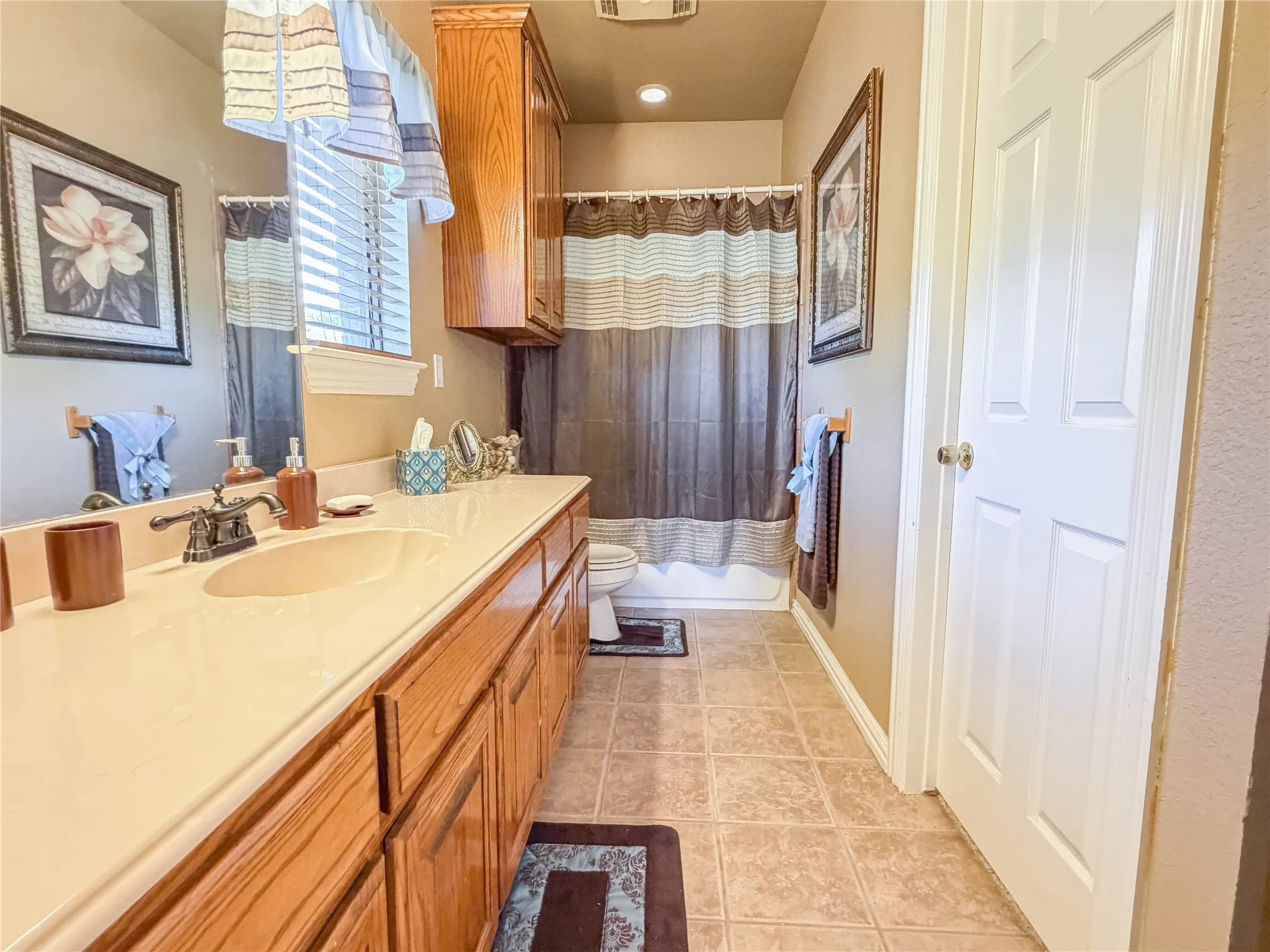 Tiled flooring, elongated single vanity with integrated sink, wood cabinetry, built-in medicine cabinet, and bathtub with shower
