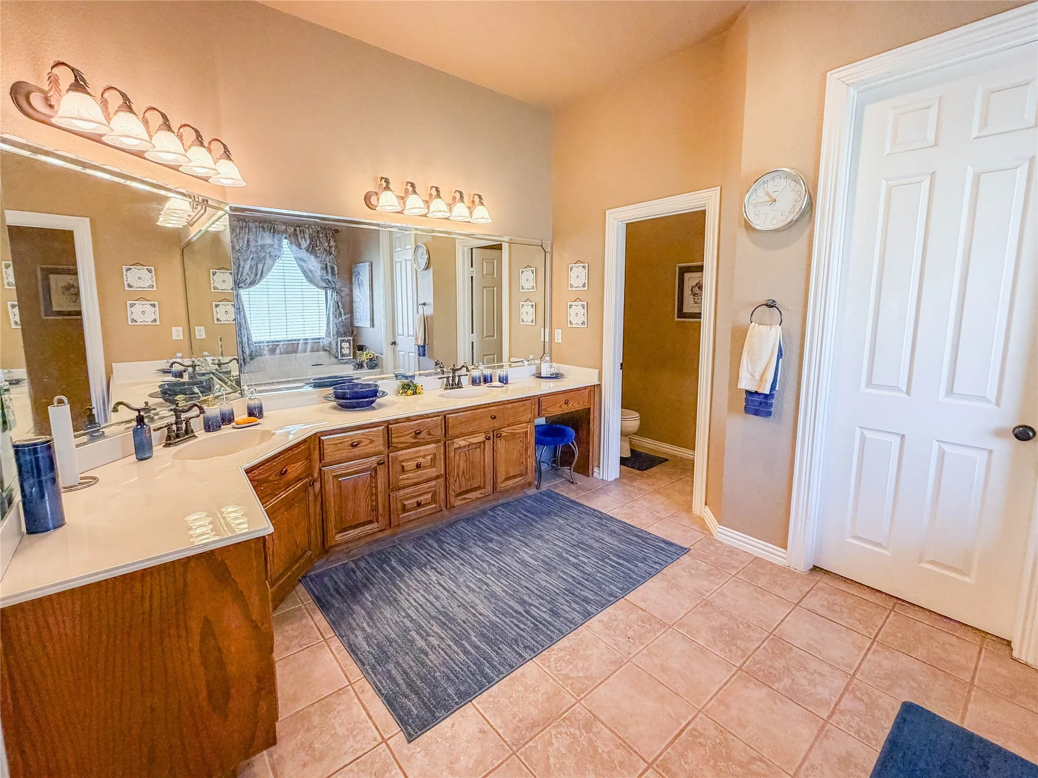 Dual vanity with integrated sinks, expansive counter space, wood cabinetry, and tile flooring
