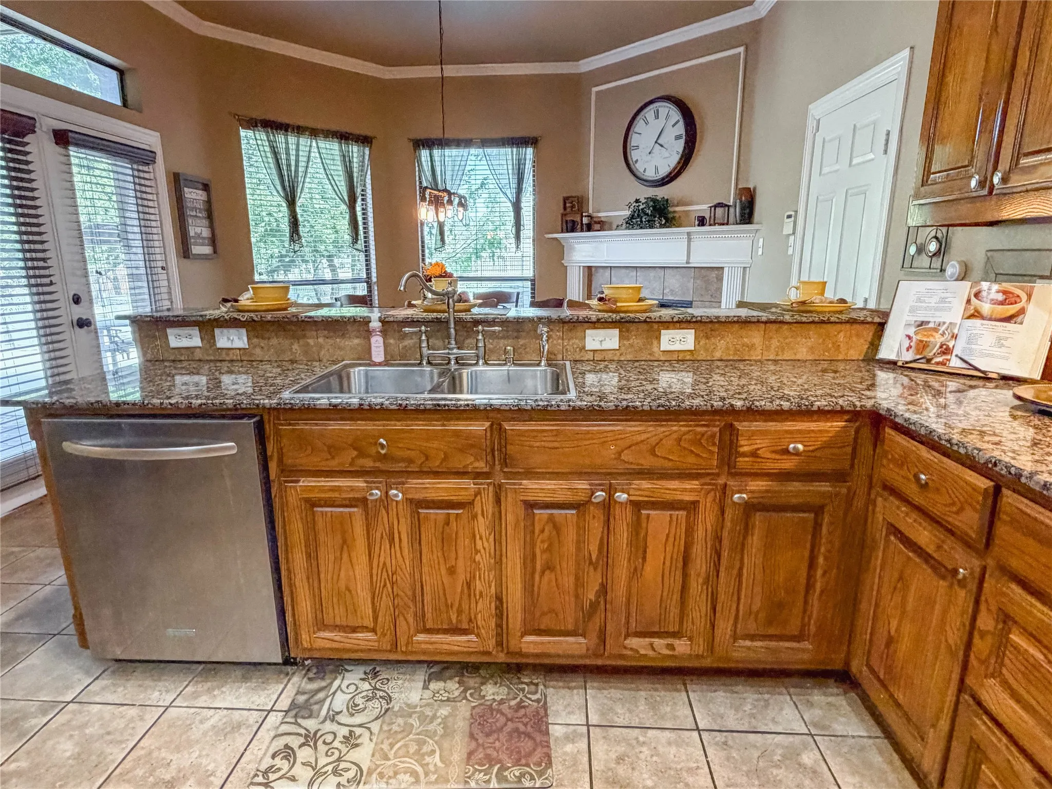 Kitchen featuring wood cabinetry, granite countertops, a stainless steel double sink, and a stainless steel dishwasher