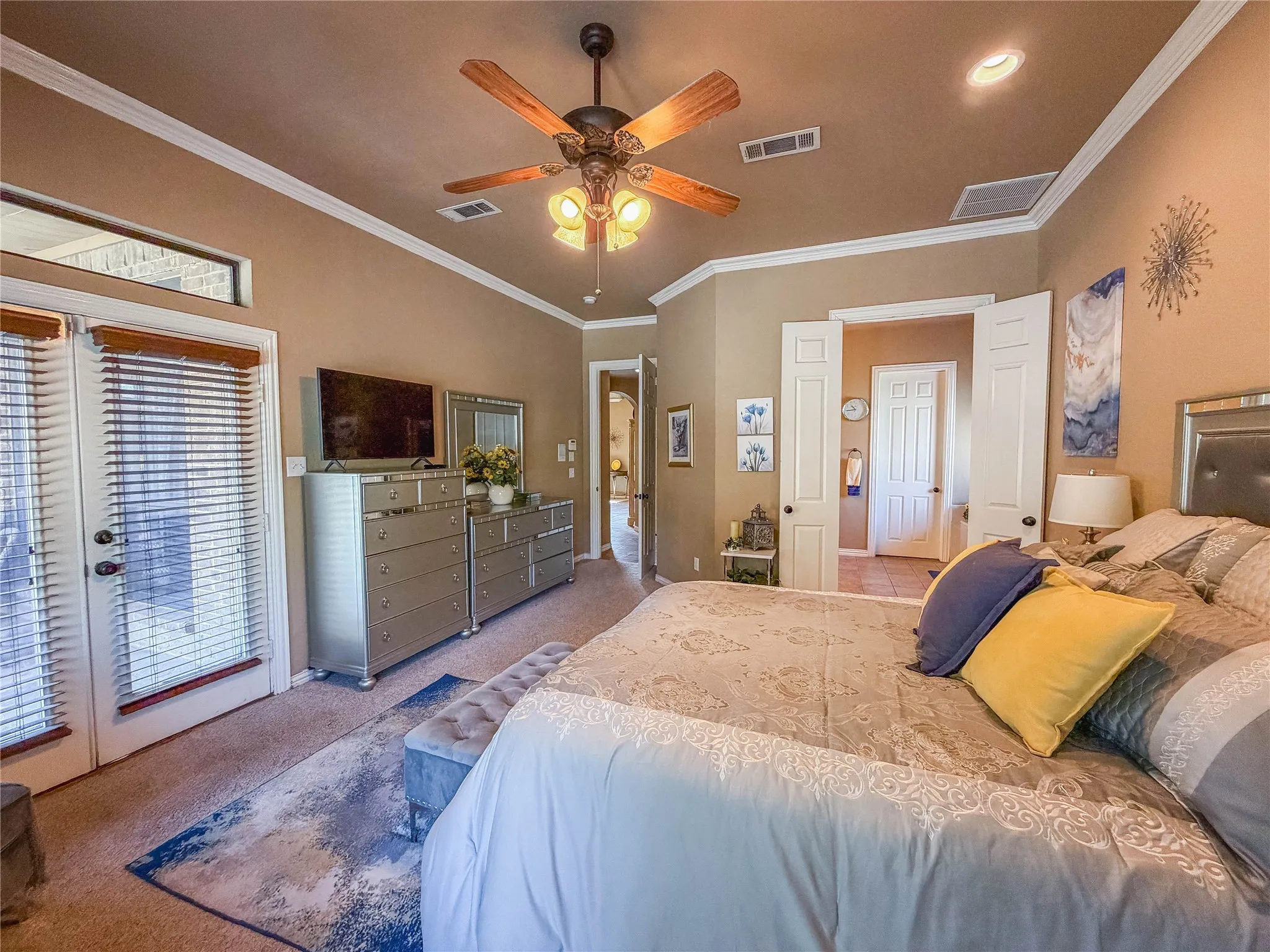 Crown molding accents a neutral-toned room with a ceiling fan