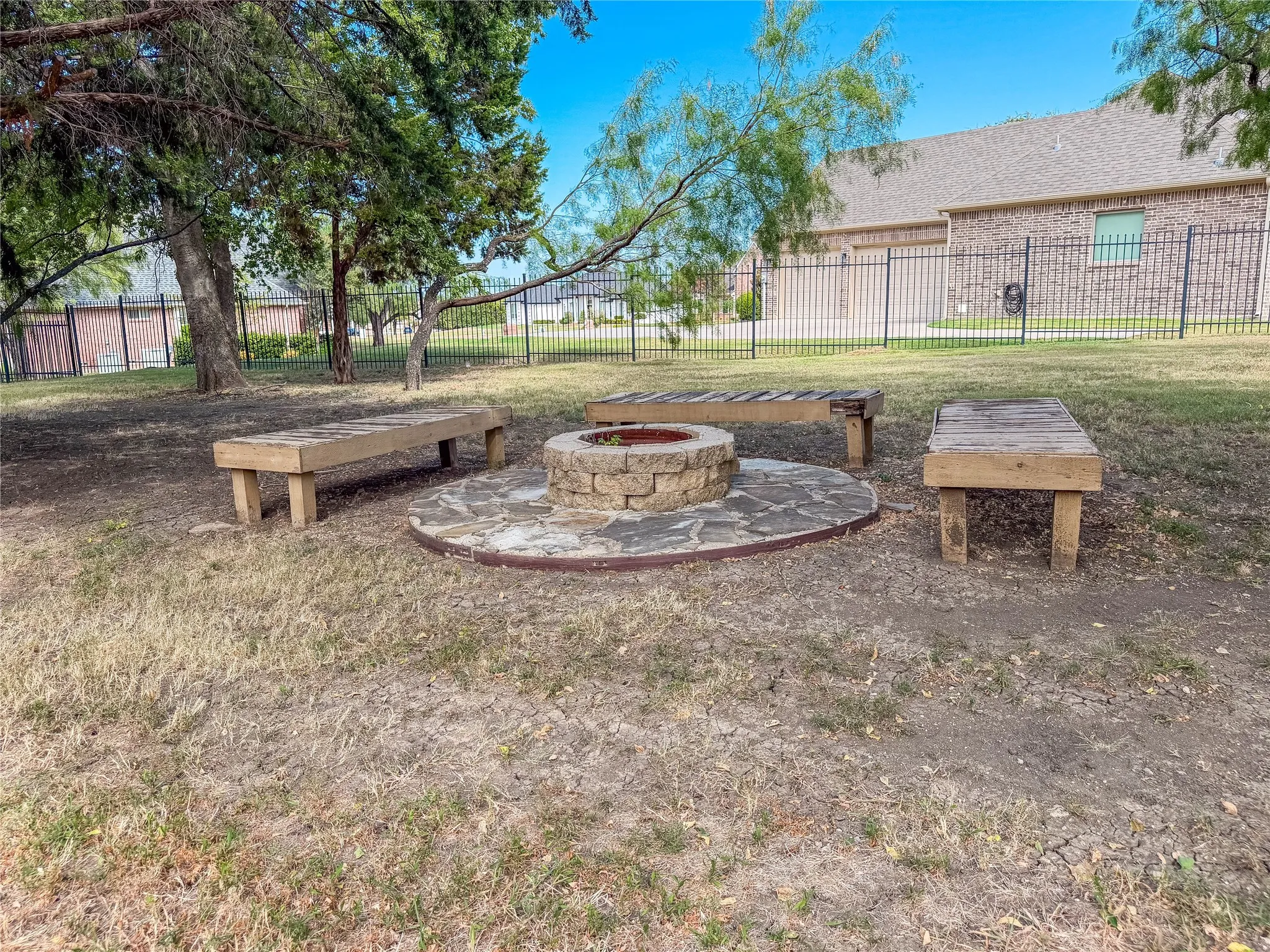 Outdoor gathering area featuring a stone fire pit, flagstone base, and three wooden benches