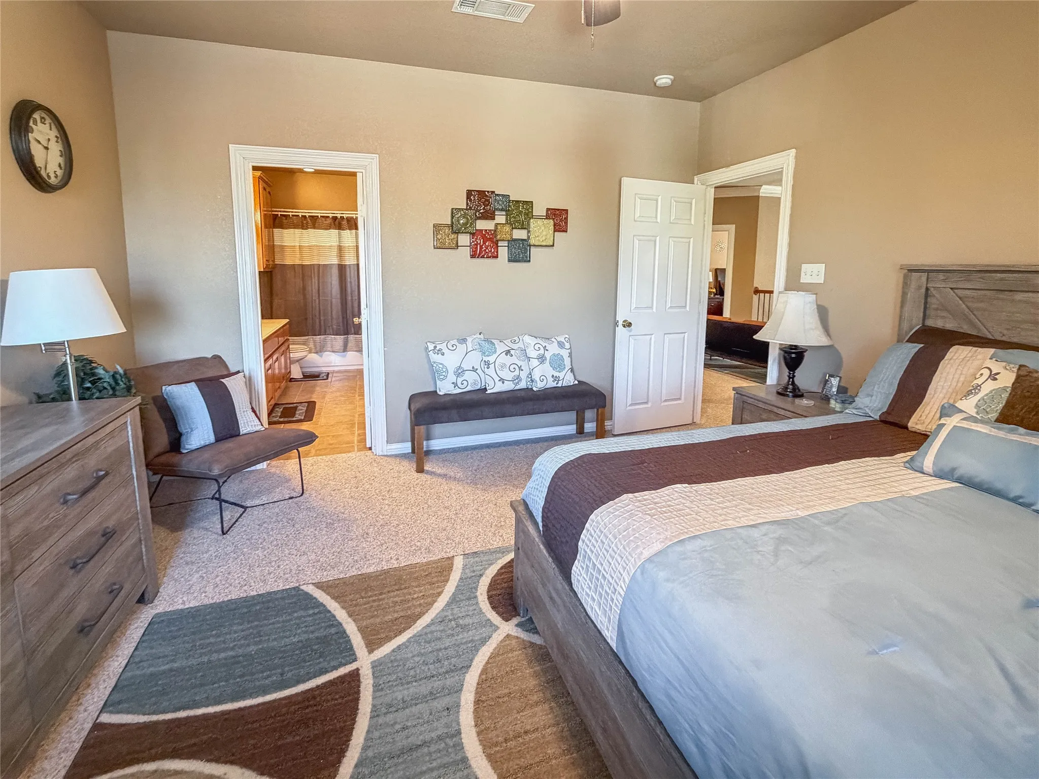 Carpeted flooring, ceiling fan, wood-finish headboard, built-in vanity, tile flooring in bathroom