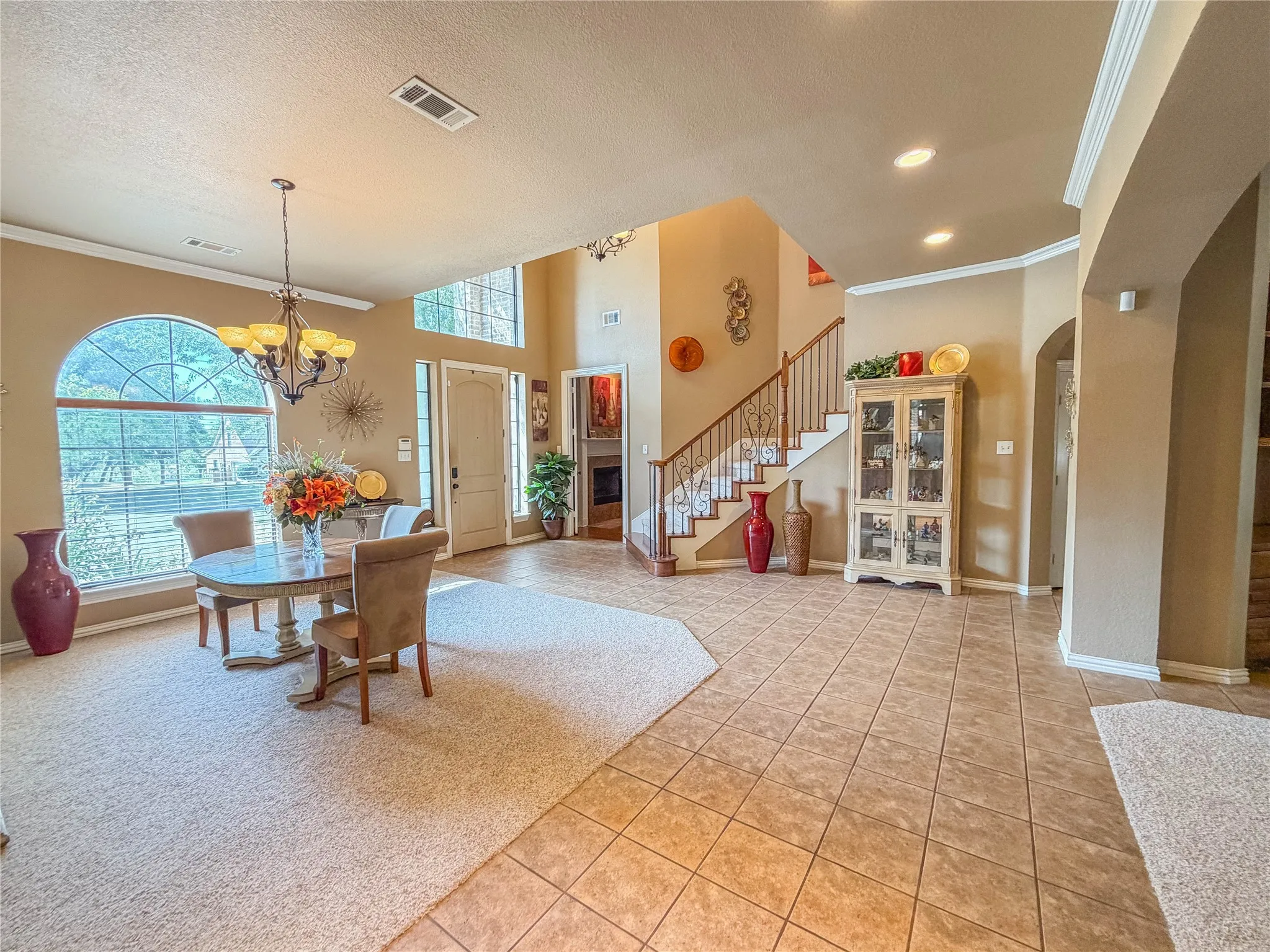 Two-story foyer with tile flooring, an arched window, a wrought iron staircase, a recessed ceiling, and an arched entry