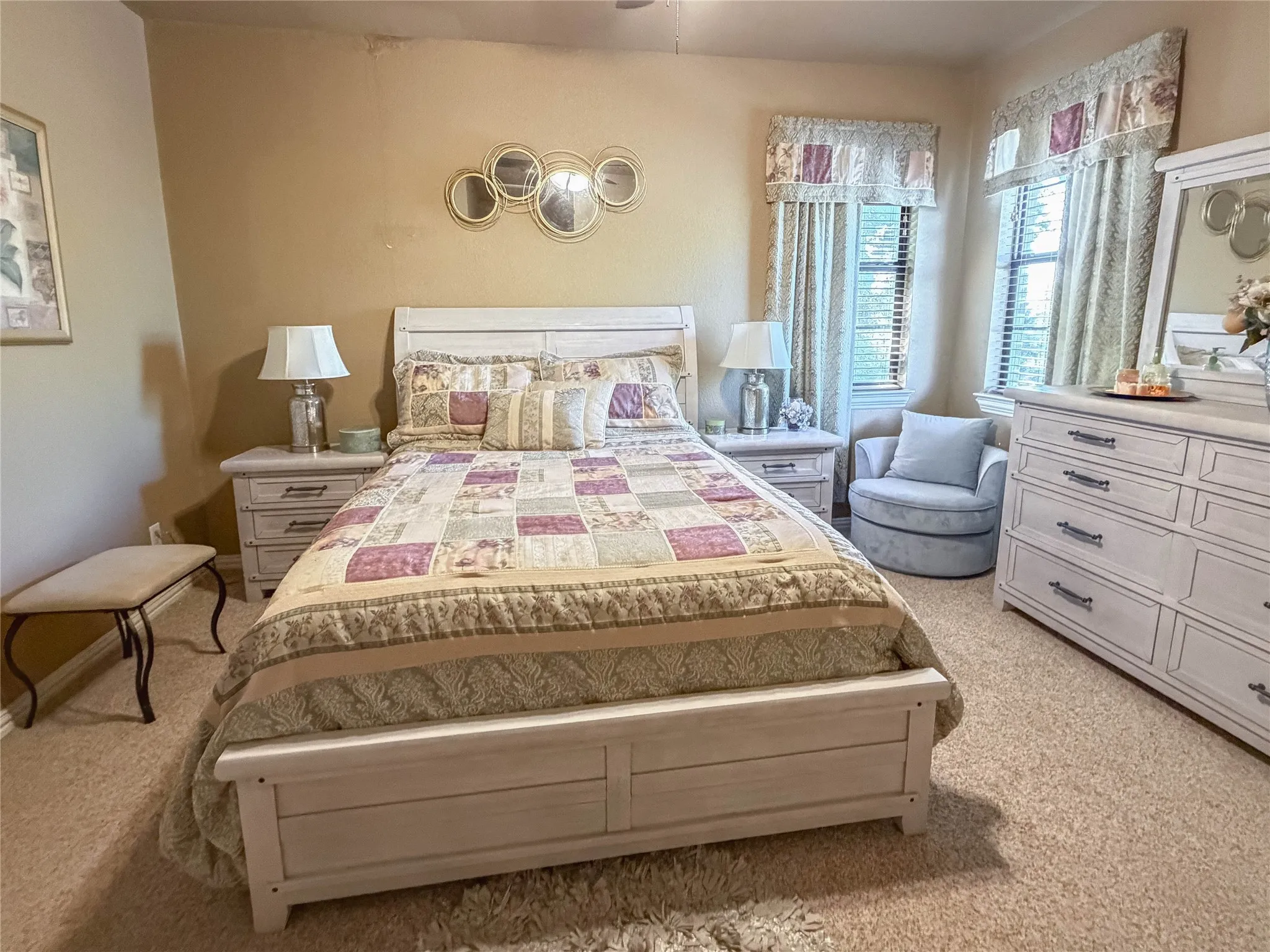 Carpeted room featuring dual windows with blinds, a ceiling fan, and wall-mounted decorative mirrors