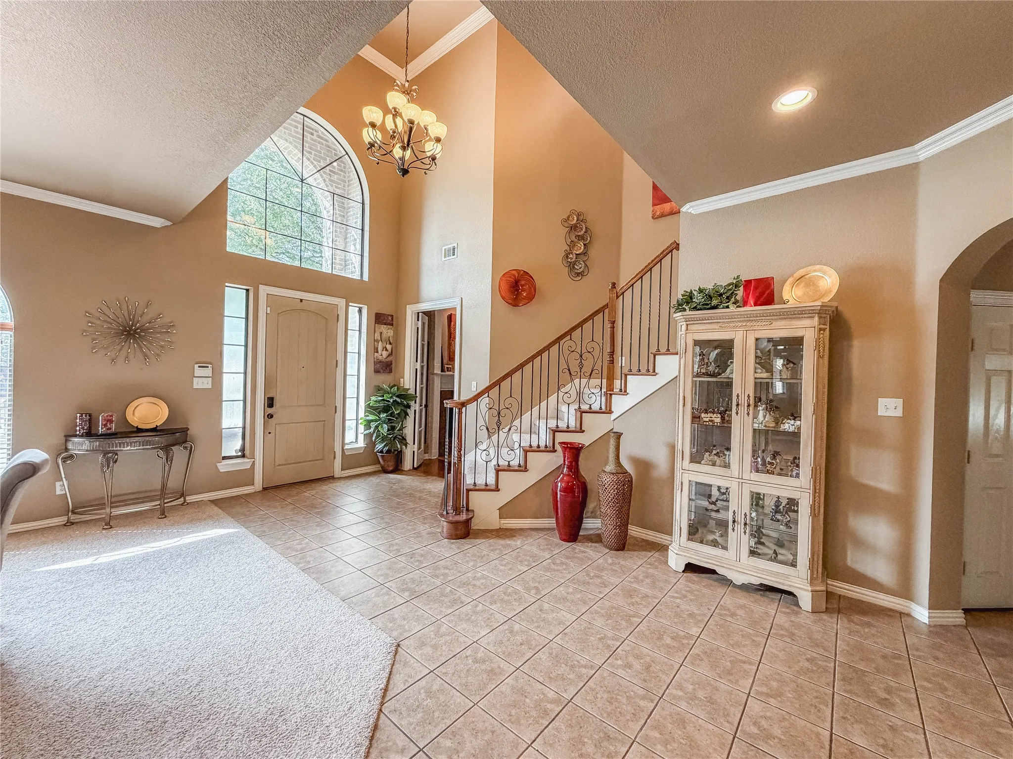 Two-story entryway featuring a prominent arched window and a chandelier