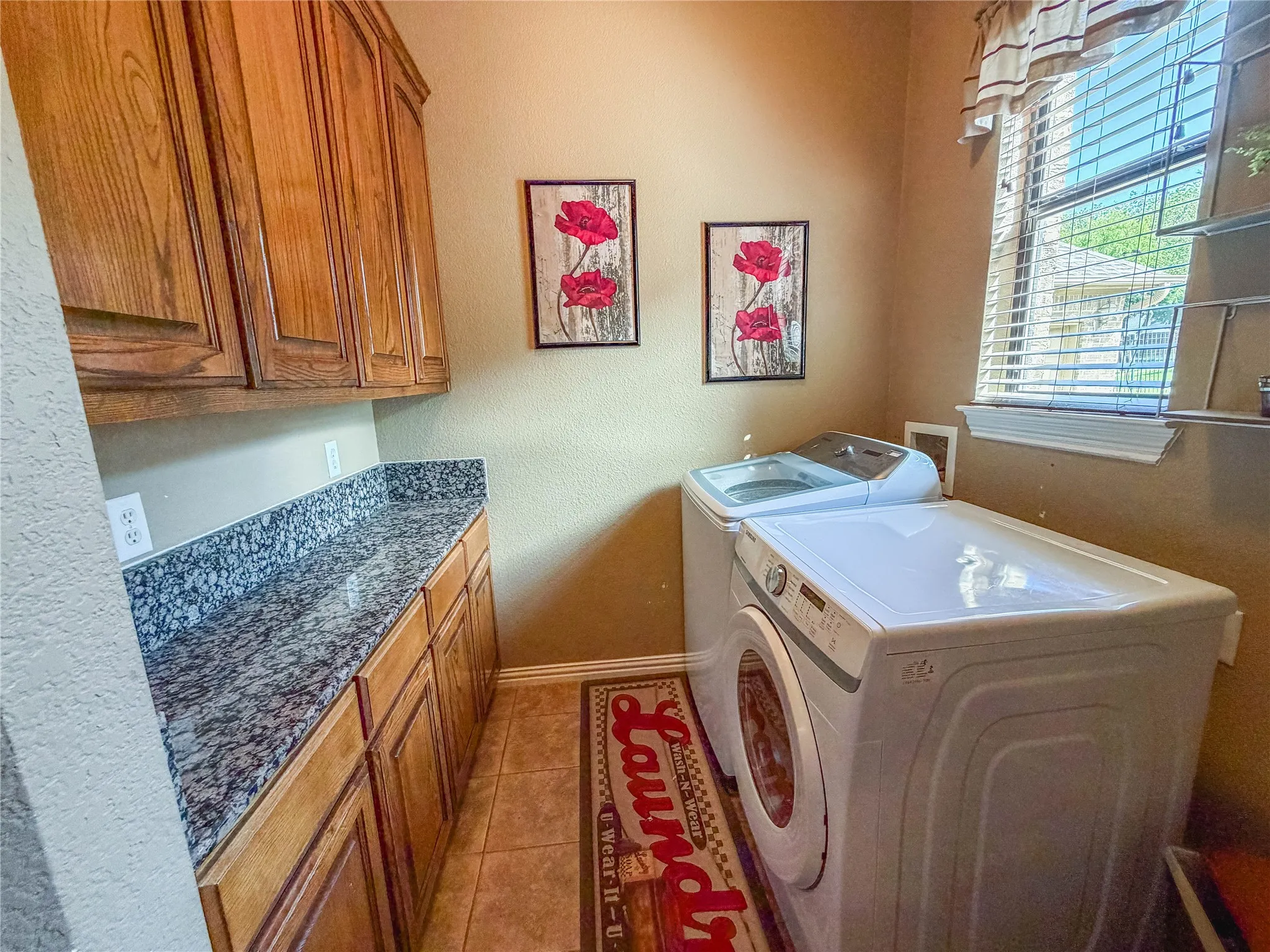 Utility space featuring wood cabinetry, a stone-finish countertop, and tile flooring