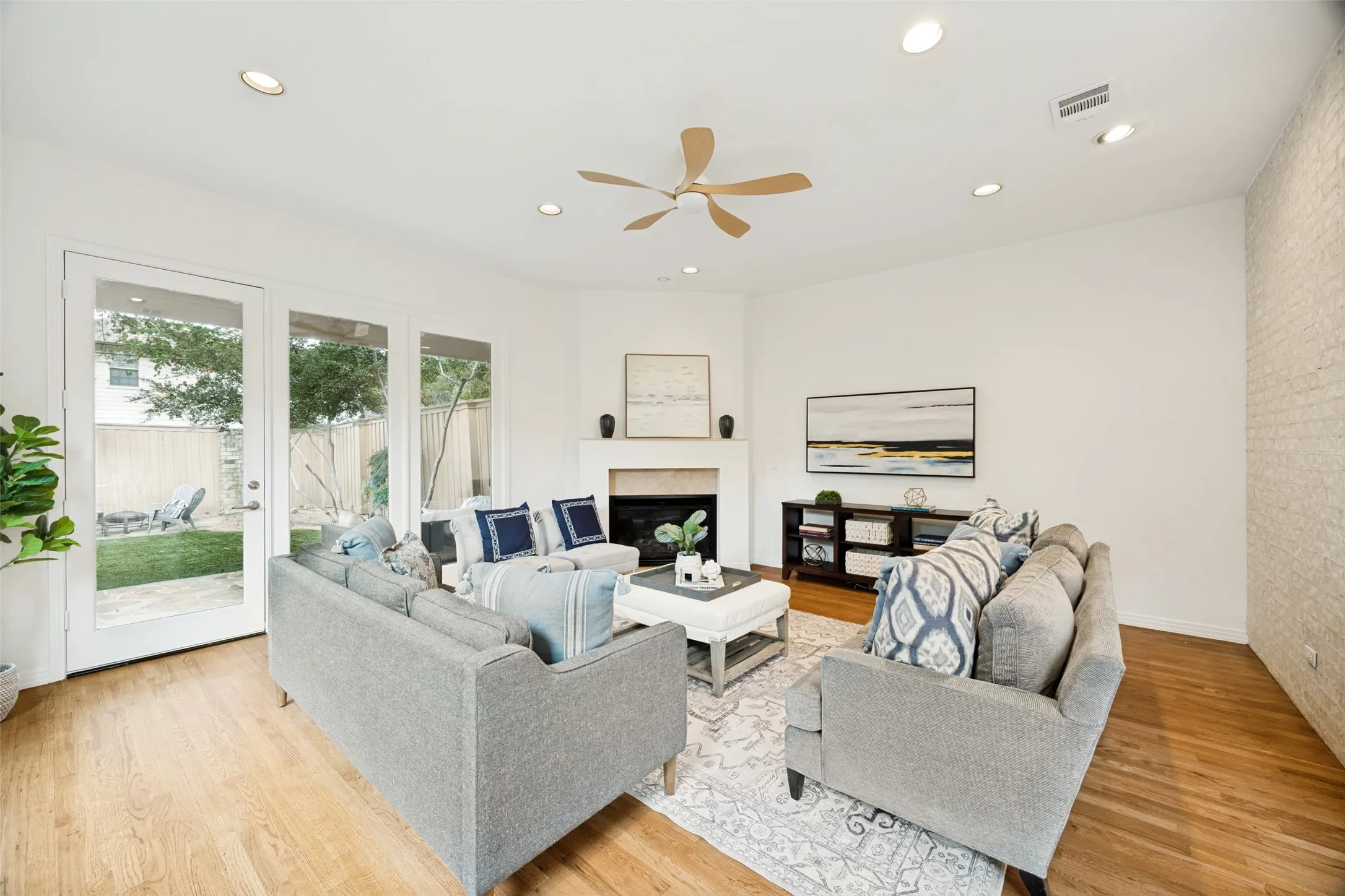 Stunning living room with brick accent wall, fireplace and a wall of windows overlooking the spacious backyard