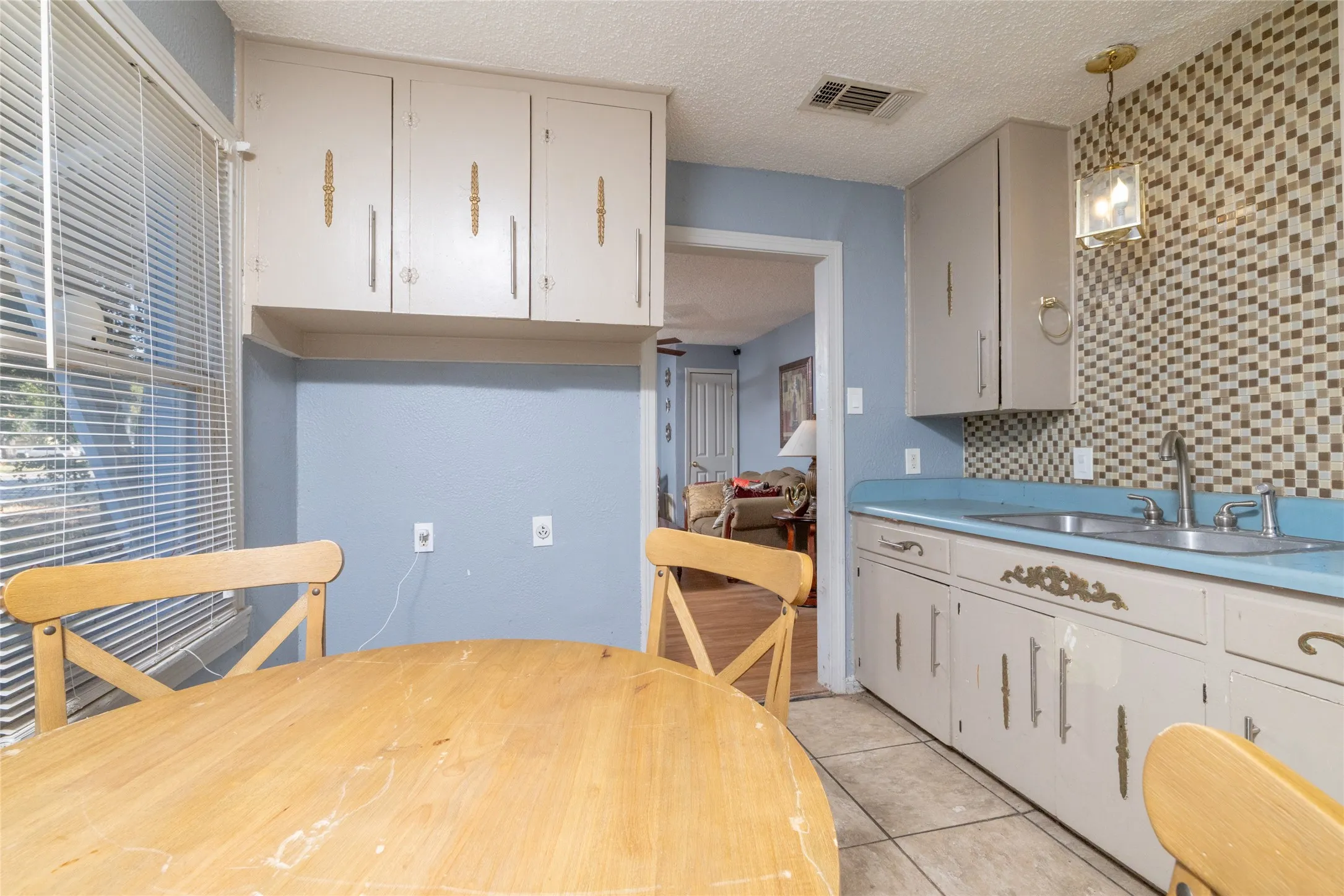 Kitchen featuring tile flooring, mosaic tile backsplash, double basin sink, and pendant light fixture