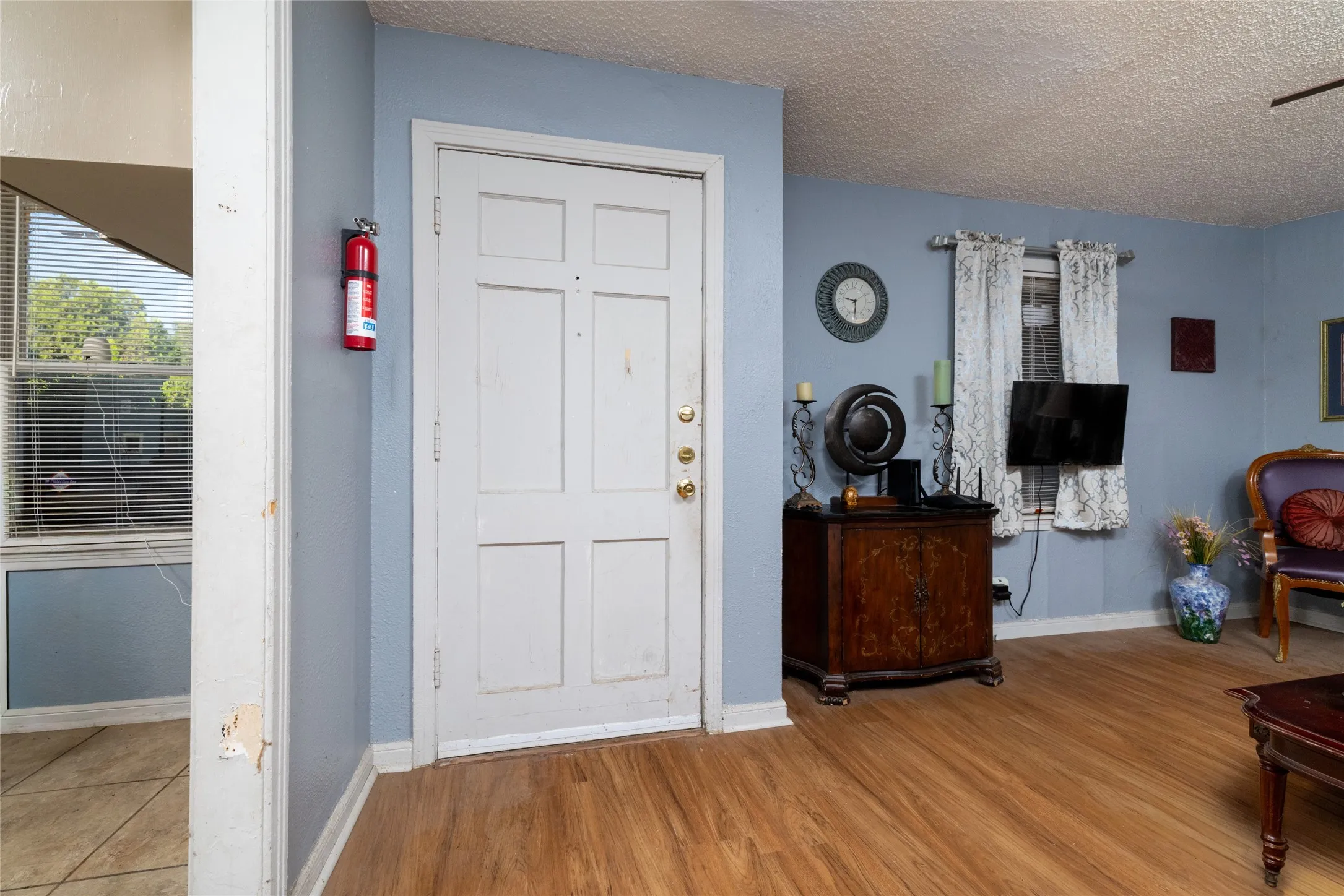 Wood-finish flooring throughout, light blue wall paint, and a textured ceiling