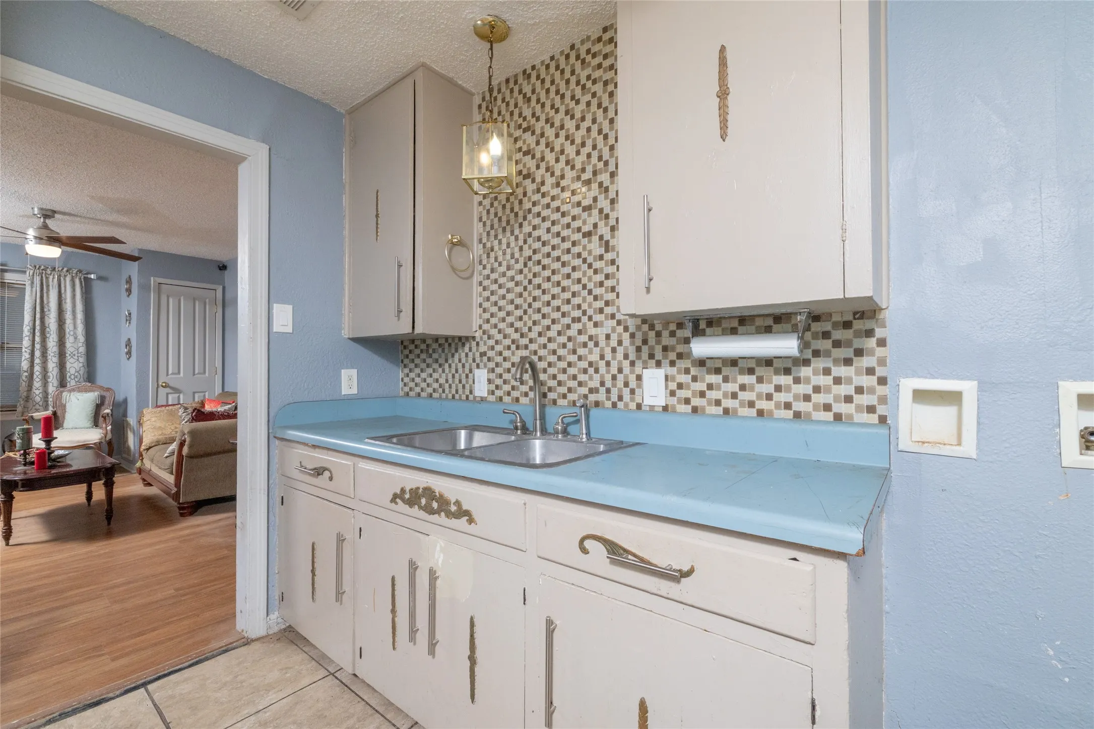 Kitchenette featuring white cabinetry, a blue countertop, stainless steel sink, and mosaic tile backsplash