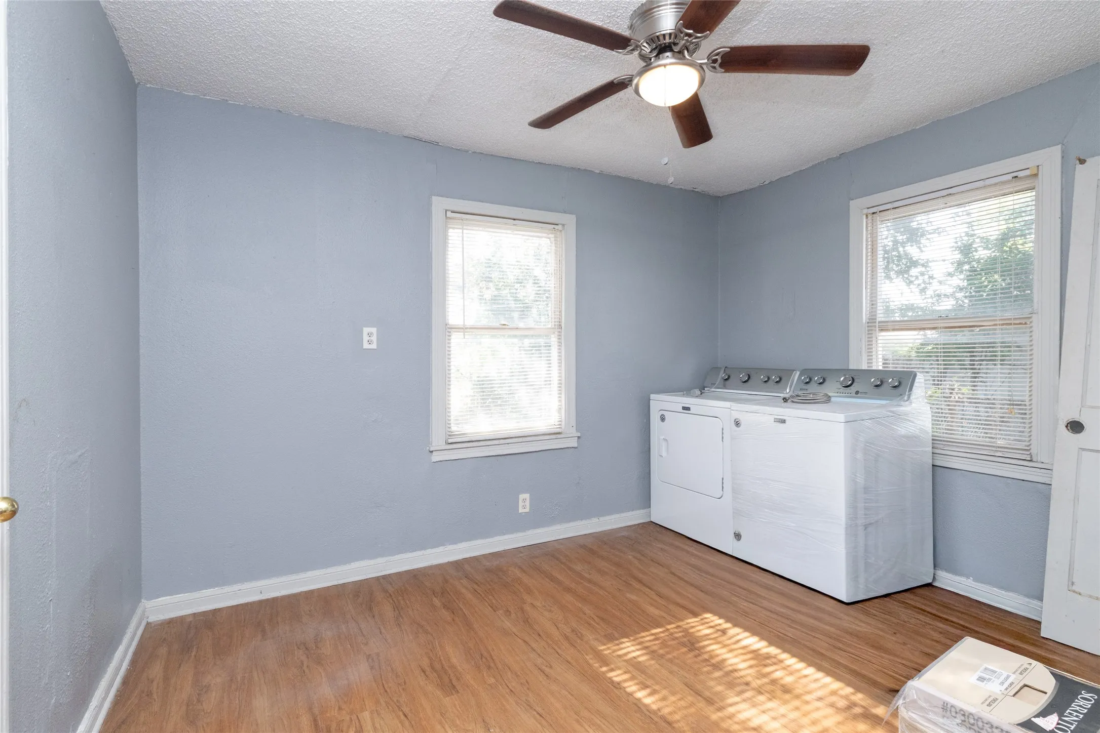 Wood-finish flooring, two windows, and a ceiling fan with light fixture