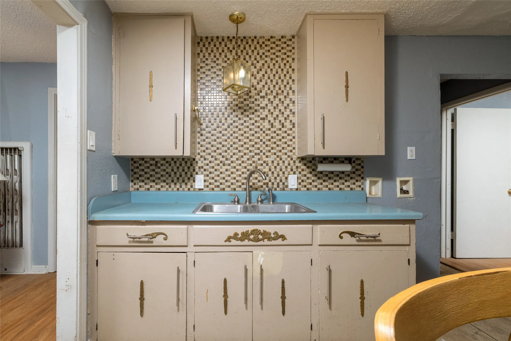 Kitchenette with a stainless steel sink, mosaic tile backsplash, and overhead lighting fixture