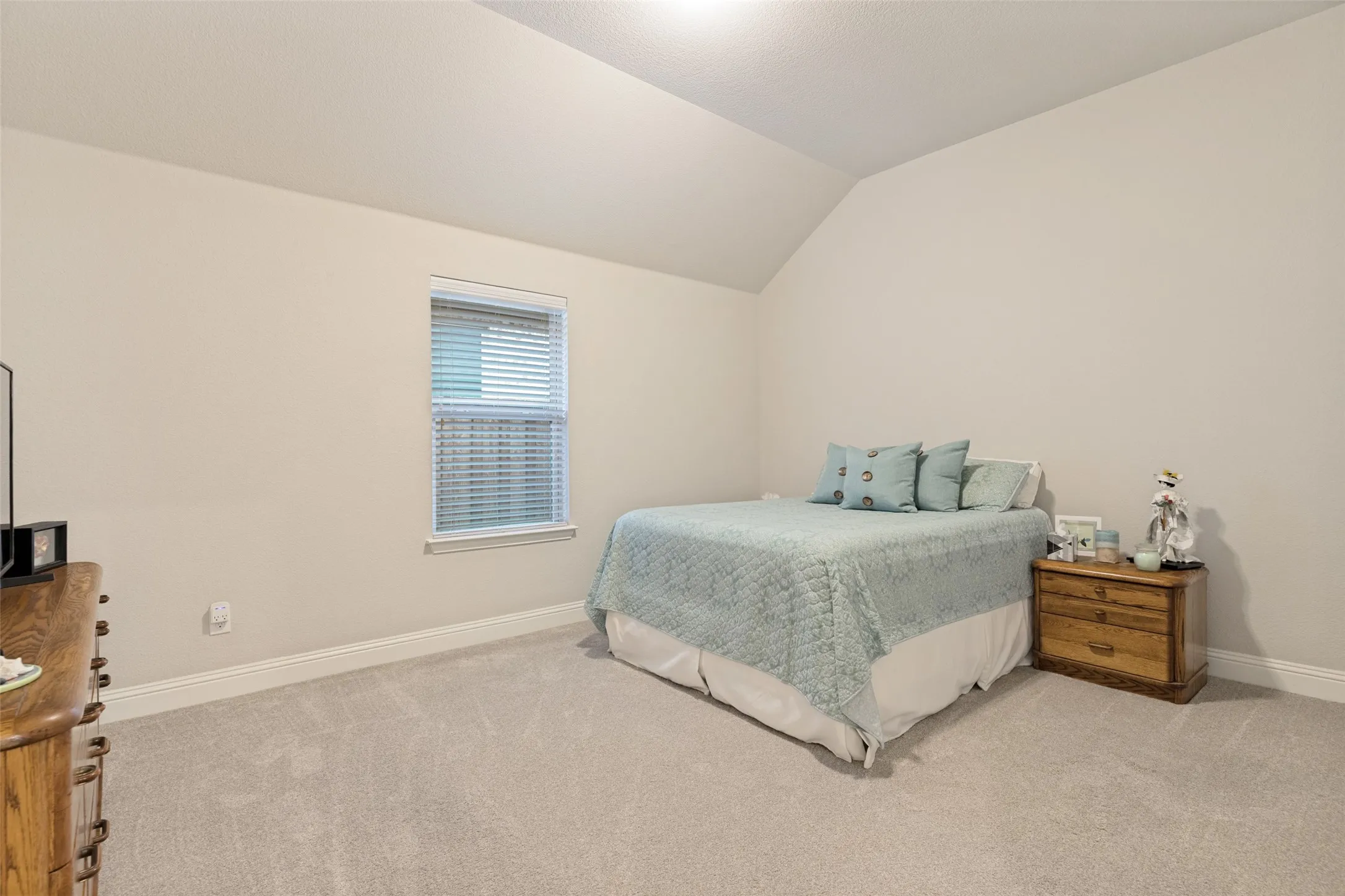 Vaulted ceiling, neutral wall paint, carpeted flooring, window with blinds