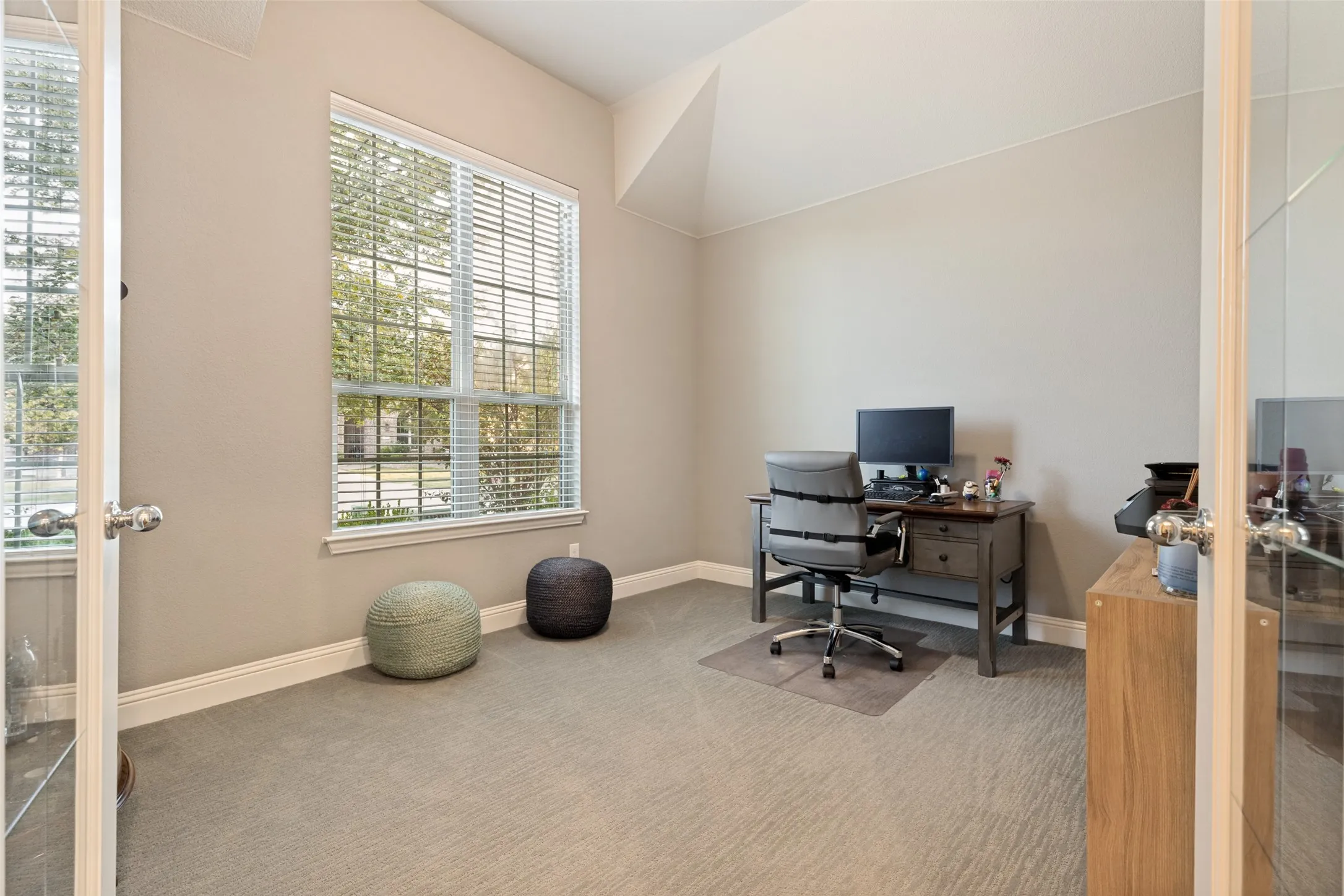 Recessed lighting, sloped ceiling, large window with blinds, luxury carpet flooring, and a glass-paneled door
