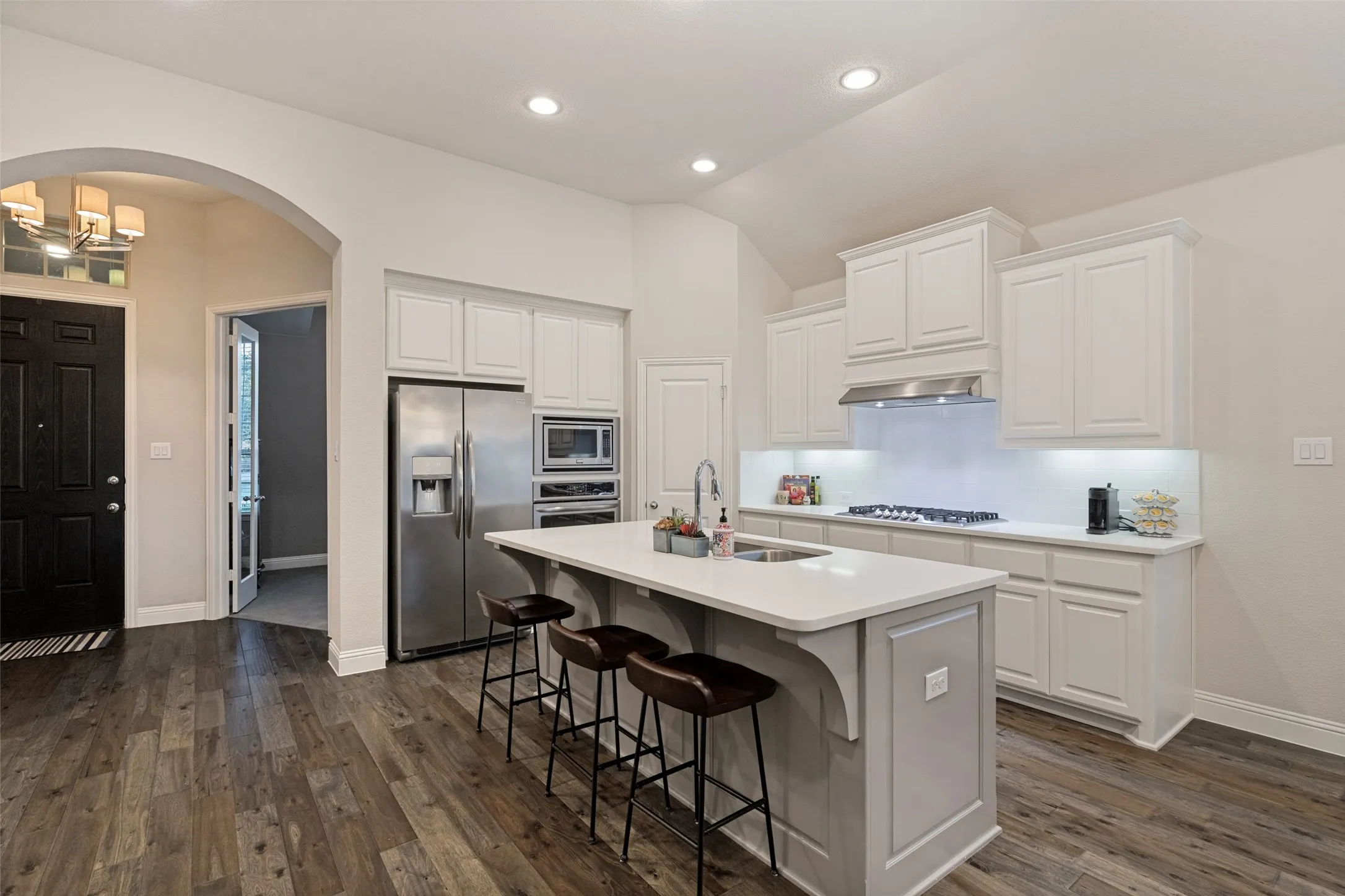 Modern kitchen featuring luxury vinyl flooring, solid wood cabinetry, a built-in stainless steel microwave and oven, and a kitchen island with seating