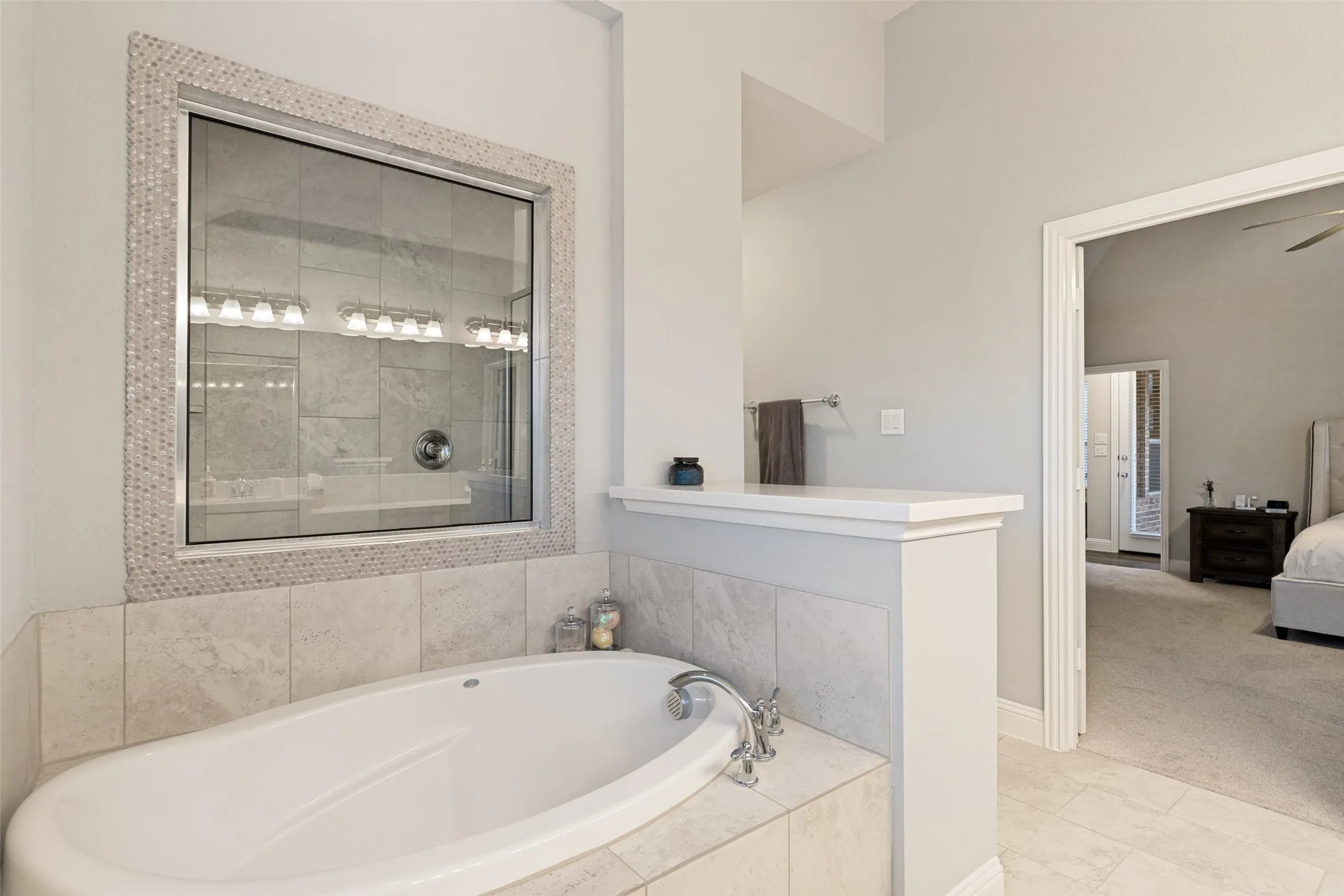 Built-in soaking tub with a tiled surround, framed by a mosaic-tiled window