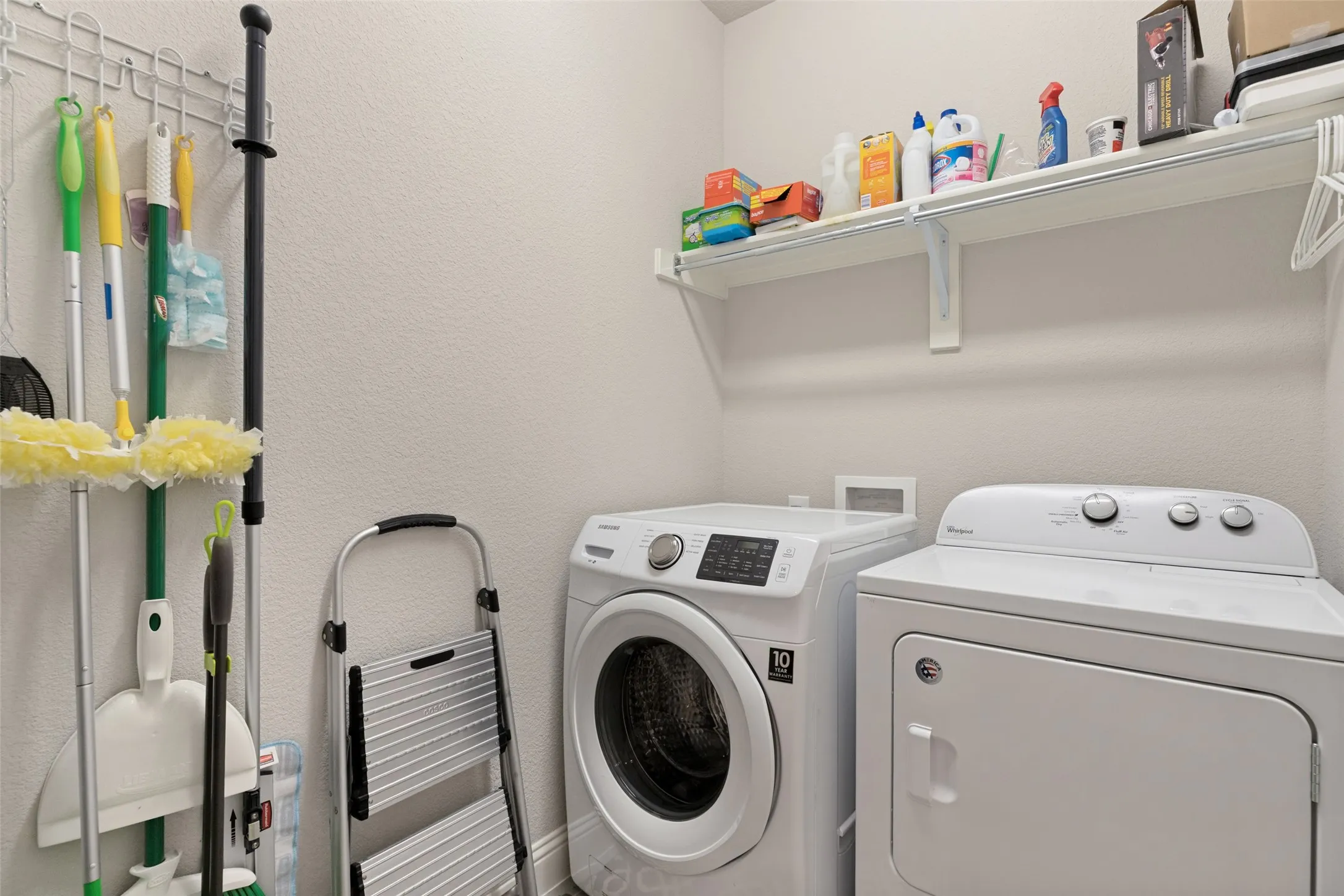 Dedicated laundry space with built-in shelving and appliance hookups